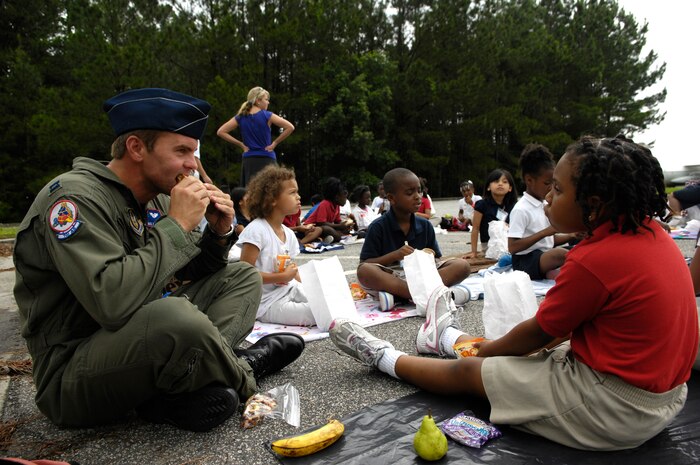 U.S. Air Force Capt. Nate Arkwood joins approximately 260 students from North Charleston Elementary School for a bag lunch at Joint Base Charleston, S.C., May 26, 2010. The students visited the base as an educational reward for completing the "Revving It Up For Reading" program. This also provided a mentoring opportunity for the base's military members. The reading program encourages children to read at least 25 books throughout the school year. Captain Arkwood is a C-17 pilot with the 701st Airlift Squadron. (U.S. Air Force Photo/Airman 1st Class Lauren Main)