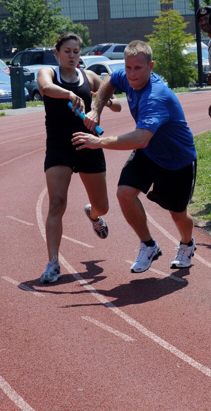 LANGLEY AIR FORCE BASE, Va. -- 1st Lt. Krista Barajas, 633d Force Support Squadron fitness assessment cell officer in charge, passes the baton to Chris Bendix, 633d Force Support Squadron fitness testing technician, during the Squadron Fitness Challenge 1.5 mile relay run May 27. The Squadron Fitness Challenge is an annual event wrapping up May fitness month and was hosted by the 633d Force Support Squadron and Prism Sports to promote a healthy, active lifestyle.  (U.S. Air Force Photo/Staff Sgt. Christina M. Styer) 