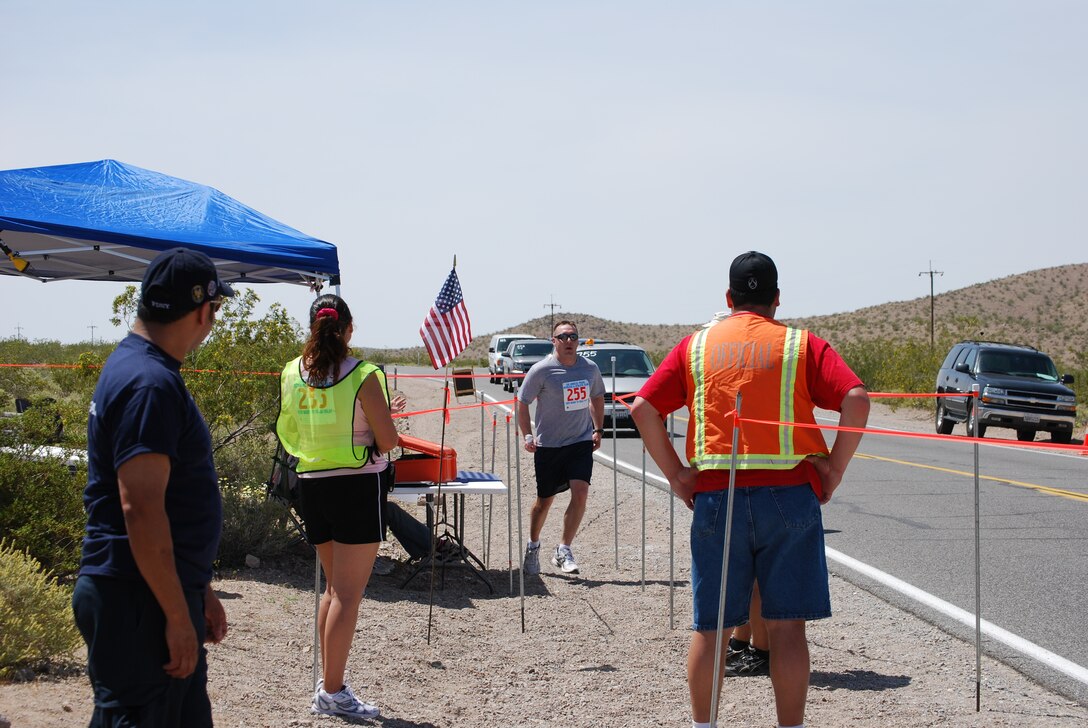 Justin Brodrick (third from left), member of team LAAFB, finishes his leg as Josie Fonseca (second from left) is ready to "catch" him while race officials look on during the 26th Annual "Baker to Vegas" Challenge Cup Relay Race April 17 and 18, 2010. (Courtesy photo)