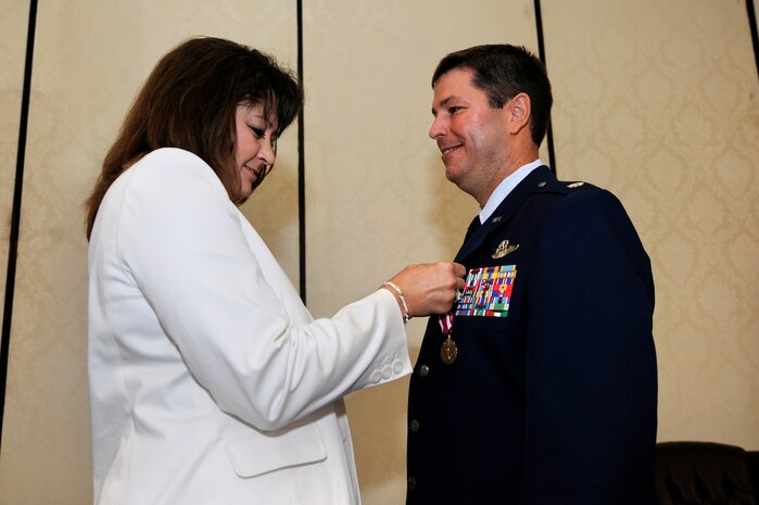 U.S. Air Force Lt. Col. Jesse Strickland receives a retirement pin from his wife Janice at Joint Base Charleston, S.C., May 27, 2010, after more than 22 years of dedicated service. One of his many career accomplishments included holding responsibility for the qualification and combat readiness of more than 850 C-17A aircrew members conducting airlift, aerial delivery and aerial evacuation missions worldwide. (U.S. Air Force photo by James M. Bowman/Released)