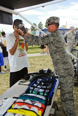 ALAMOGORDO, N.M. -- Senior Airman John Buckley, 49th Civil Engineering Squadron, helps a spectator try on a protective mask at the Chemical Biological Radiological Nuclear Trailer and Display during Alamogordo?s Armed Forces Day Celebration May 15, 2010. This display was one of several from Holloman Air Force Base Airmen who participated in Alamogordo's salute to the military. (U.S. Air Force photo by Tom Fuller / Released)