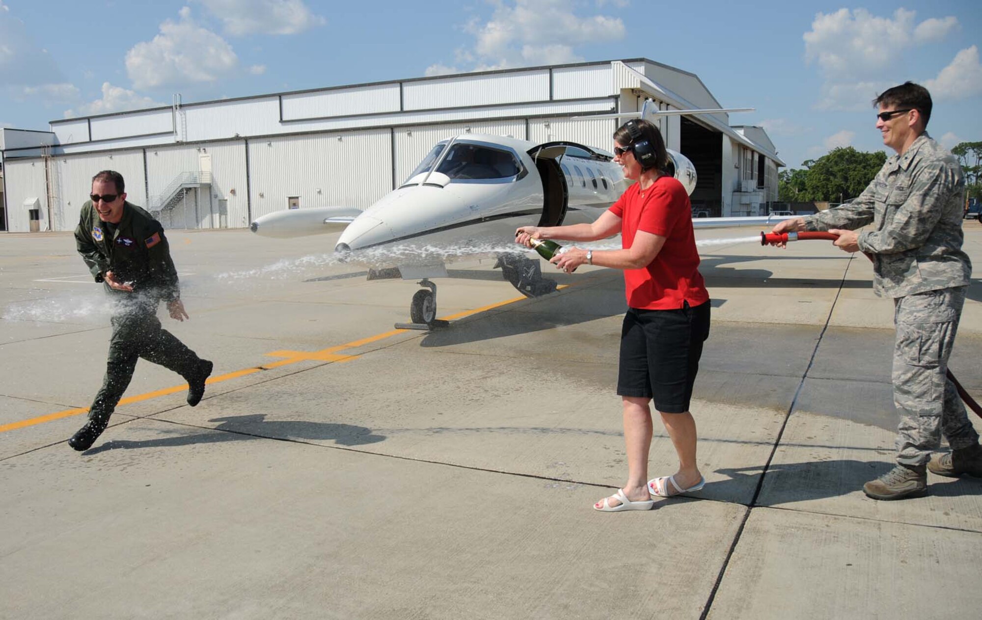 Col. Chris Valle, 81st Training Wing vice commander for the past two years, is sprayed with champagne by his wife, Mary, and soaked with a fire hose by Brig. Gen. Ian Dickinson, 81st TRW commander, after his final flight as an Air Force pilot in a C-21 May 27.  The colonel, an Air Force Academy graduate who retires Sept. 1 with more than 25 years of Air Force service, is a command pilot with more than 4,200 flying hours in the C-141B, C-20A and C-21A. The “fini-flight” tradition of both the U.S. and Royal Australian Air Forces features the hosing to welcome a pilot home from his final flight.  (U.S. Air Force photo by Kemberly Groue)