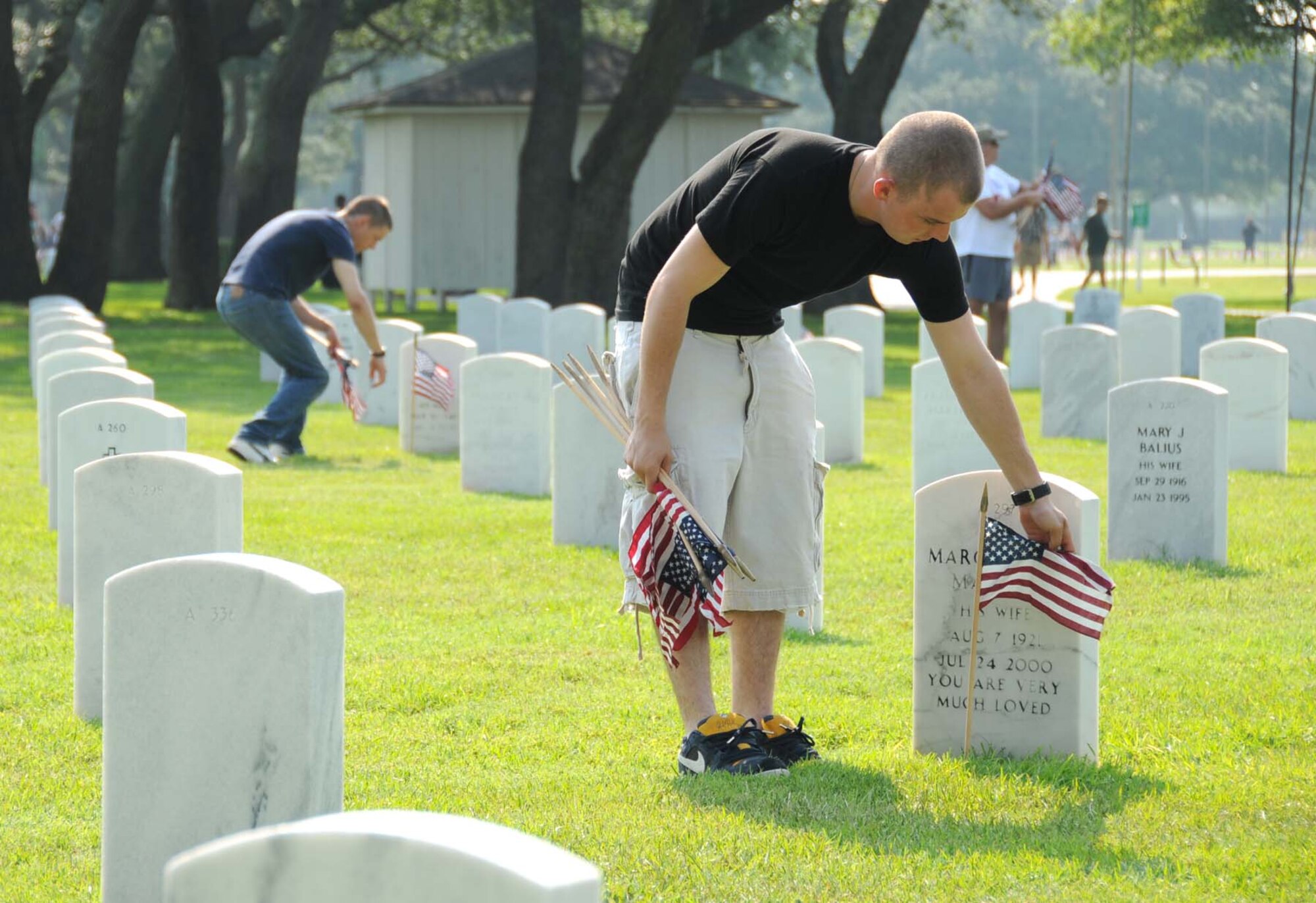 Airmen Basic Nathan Cain, left, and Tyler Smith, students from the 332nd Training Squadron, were among the Team Keesler members who joined hundreds of base and community volunteers Saturday in placing flags on about 16,560 graves at Biloxi National Cemetery in preparation for Memorial Day.  Maj. Gen. Mary Kay Hertog, 2nd Air Force commander; Col. Chris and Mary Valle, 81st Training Wing vice commander; Chief Master Sgt. Curtis Jennings, 81st Mission Support Group superintendent, and Chief Master Sgt. David and Linda Kendall, Mathies NCO Academy commandant, represented Keesler at the cemetery’s ceremony Monday.  (U.S. Air Force photo by Kemberly Groue)