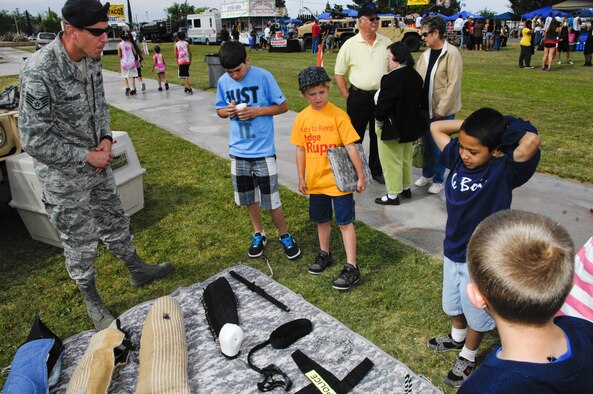 ALAMOGORDO, N.M. -- Staff Sgt. Christopher Spradley, 49th Security Forces Squadron, explains a dog handler's gear display to kids during Alamogordo's salute to the military May 15, 2010. This year's Armed Forces Day exhibition included several exhibits from Holloman Air Force Base like the military working dogs. (U.S. Air Force photo by Tom Fuller / Released)
