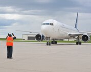 MINOT AIR FORCE BASE, N.D. -- Mark Stotesbery, a transient alert contractor with the 5th Maintenance Squadron, marshals a Boeing 767 as it departs here May 31. The 767 contains deploying members of the 5th Bomb Wing who are on a deployment rotation that provides U.S. Pacific Command with a continuous bomber presence in the Asia-Pacific region. (U.S. Air Force photo by Master Sgt. Michael Gaddis)