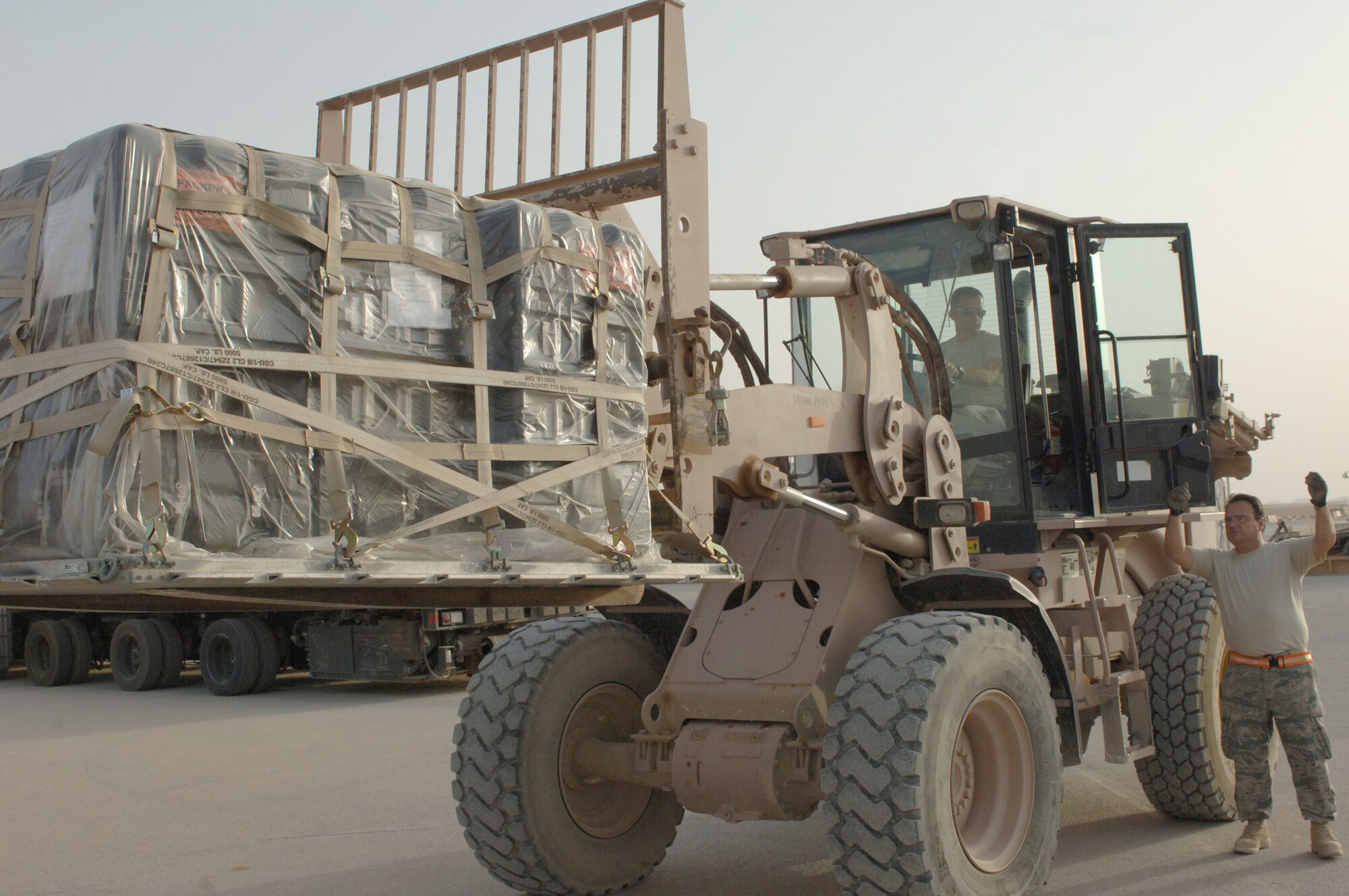 Tech. Sgt. John Leeder guides Staff Sgt. Daniel Desautels, to place cargo onto the back of a 60K aircraft cargo loader May 14, 2010,at Al Asad Air Base, Iraq. Sergeants Leeder and Desautels are 532nd Expeditionary Operations Support Squadron aerial transporters.