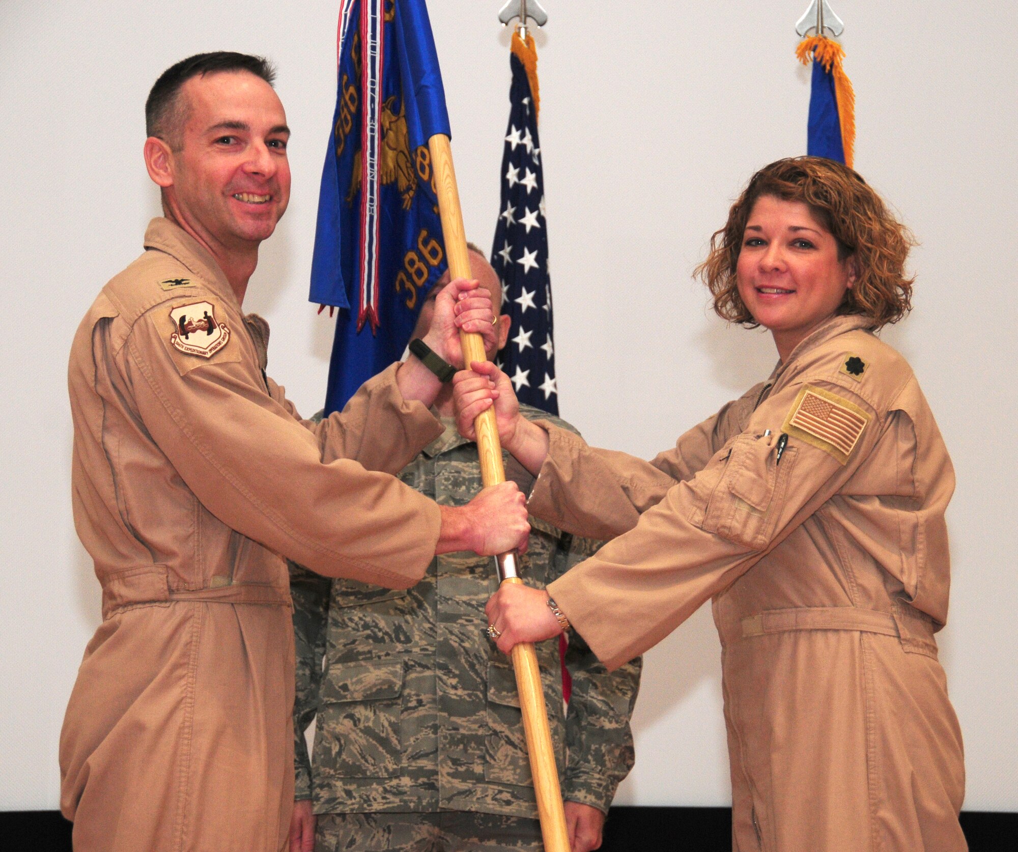 SOUTHWEST ASIA - From left, U.S. Air Force Col. Mark Czelusta, 386th Expeditionary Operations Group commander, passes the 386th Expeditionary Operations Support Squadron guidon to Lt. Col. Lynn Irwin, the new 386th EOSS commander, upon her assumption of command during a ceremony here June 2, 2010 at the base theater. Colonel Irwin assumed command after Lt. Col. Charles Bolton relinquished command. (U.S. Air Force photo by Staff Sgt. Lakisha A. Croley/Released)