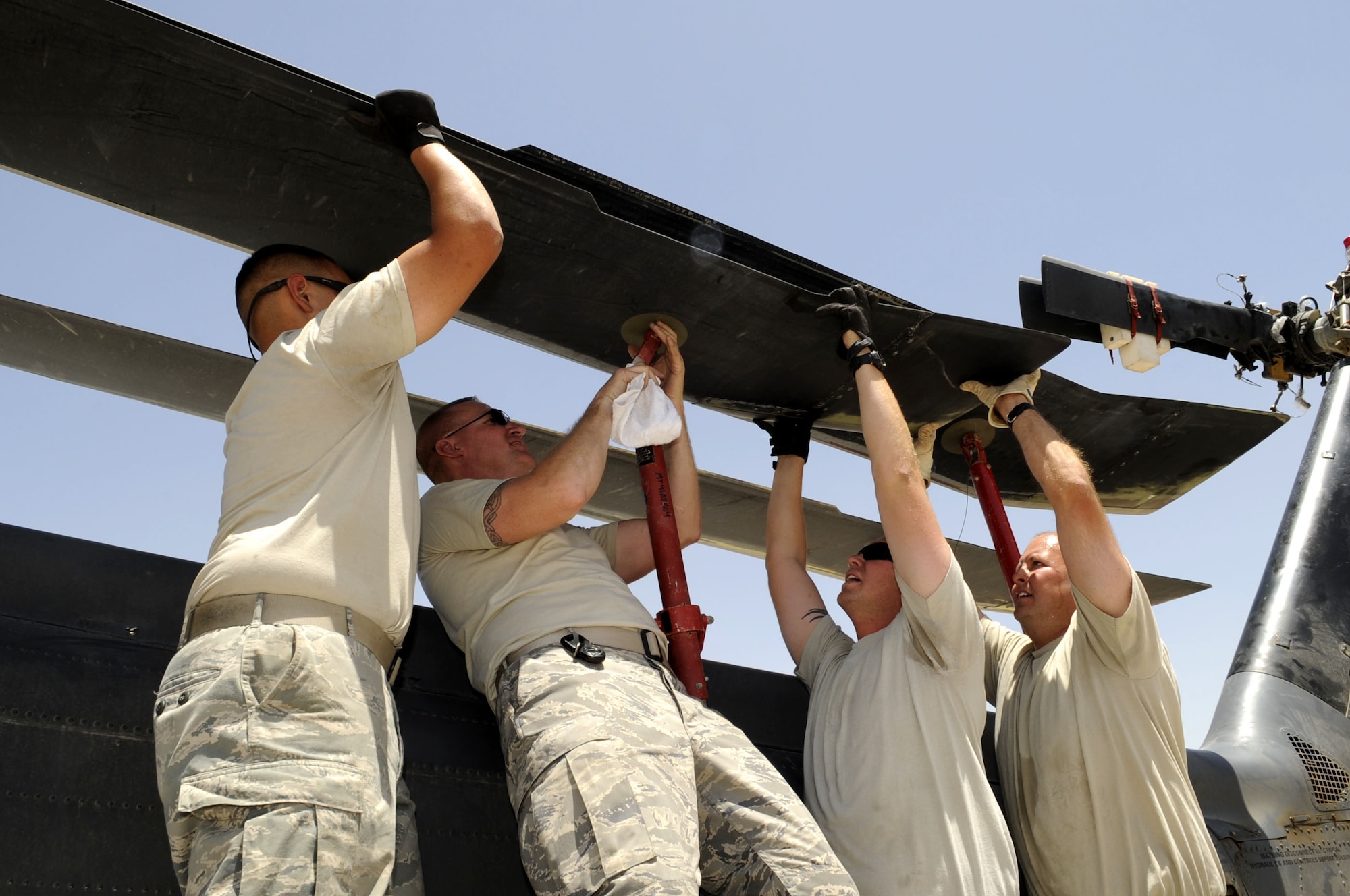 Senior Airman Adam Parra, Tech. Sgt. Michael Armstrong, Staff Sgt. Jason Paul, and Tech. Sgt. Eric Croughwell install main rotor blade fold poles May 19 while preparing an HH-60G helicopter for air shipment at Kandahar Airfield.  The helicopter will be flown to an maintenance facility on a C-17 Globemaster III for routine maintenance.  (U.S. Air Force photo by Senior Airman Nancy Hooks/Released)