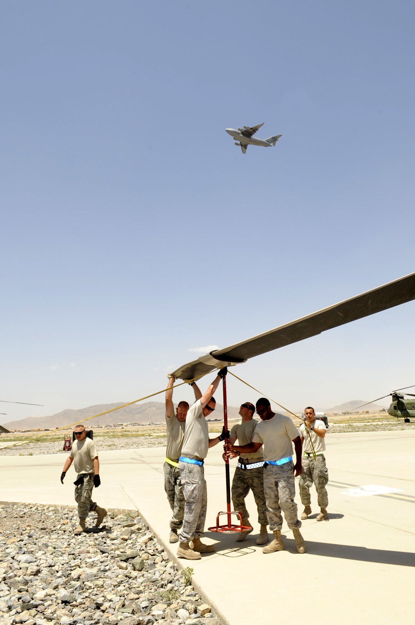 Members of the 451st Expeditionary Aircraft Maintenance Squadron fold a main rotor blade on an HH-60G Pave Hawk May 19 at Kandahar Airfield.  The helicopter is scheduled for routine maintenance and will be flown on a C-17 Globemaster III aircraft to a maintenance facility.  (U.S. Air Force photo by Senior Airman Nancy Hooks/Released)