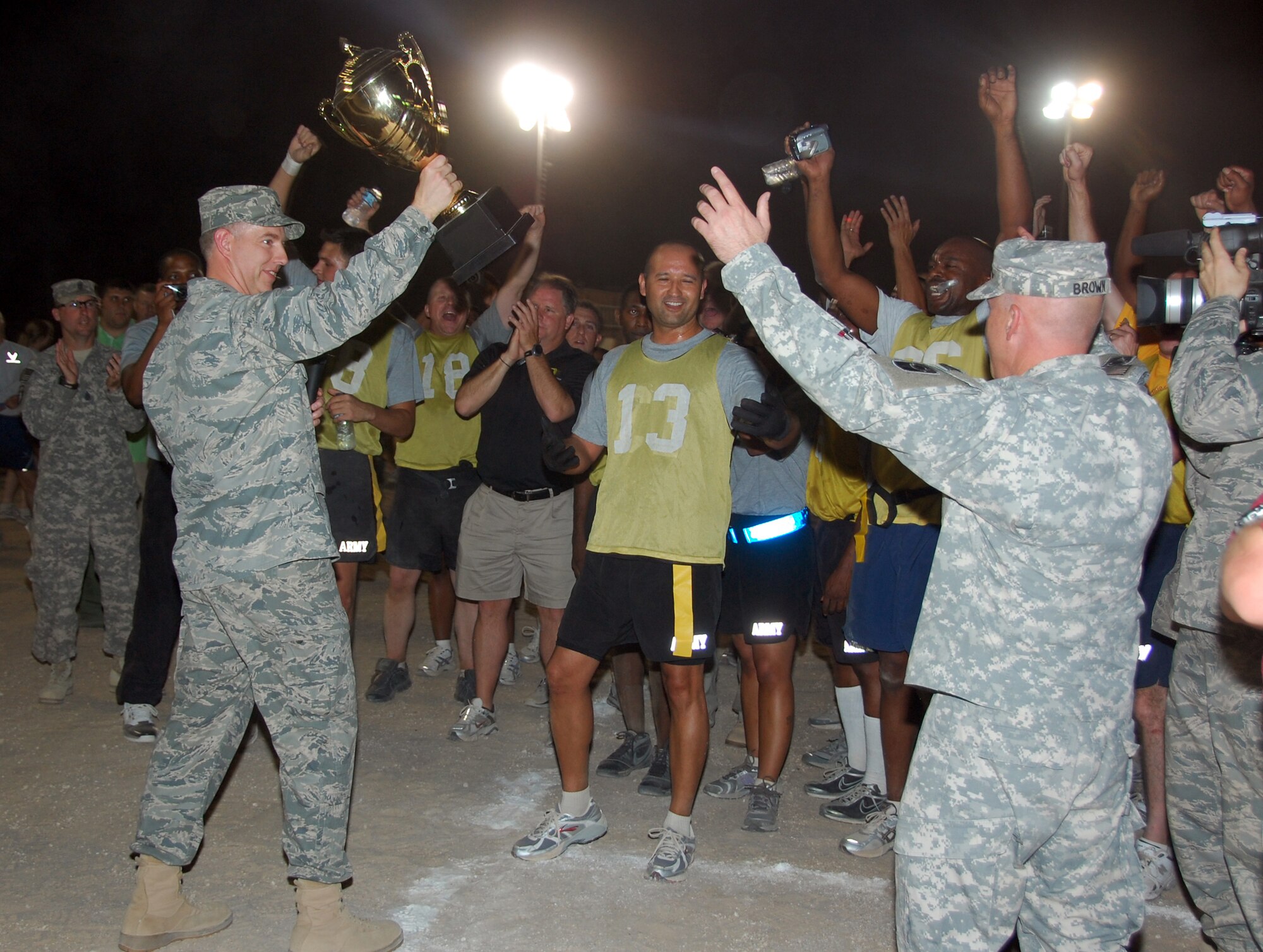 U.S. Air Force Col. John R. Gordy II, 386th Air Expeditionary Wing commander, presents the Life Support Area flag football team, made up primarily of Soldiers, with the championship trophy after the team defeated "The Rock" team, made up of Airmen, 12-8 on May 29, 2010 at an air base in Southwest Asia. College football coaches Chip Kelly, Rich Ellerson, Tim Murphy and Ron Zook coached the teams during their visit of the base as part of their tour through the U.S. Central Command area of responsibility. (U.S. Air Force photo by Tech. Sgt. Lindsey Maurice/Released) 