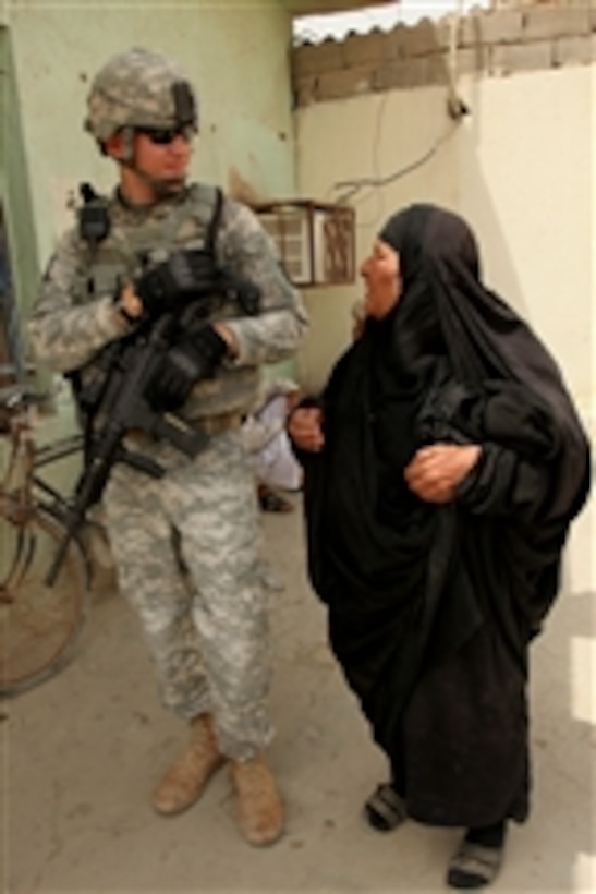 U.S. Army Staff Sgt. Samuel Ward, attached to the 17th Fires Brigade's Guardians Maneuver Element, speaks to an Iraqi woman at a bus and taxi station in Basra, Iraq, on May 23, 2010.  Soldiers conducted a combined presence patrol with Iraqi police to collect information on the city's security.  