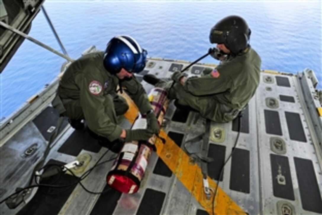 U.S. Coast Guard Petty Officer 2nd Class Allan Layne, left, and Petty Officer 3rd Class Henry Romeu prepare to drop a satellite-enabled data marker buoy from a C-130 helicopter into the Gulf of Mexico, May 29, 2010. The helicopter is from Coast Guard Air Station Clearwater, Fla. The C-130 aircrew conducted the survey flight to support the Deepwater Horizon Oil Spill Response. 