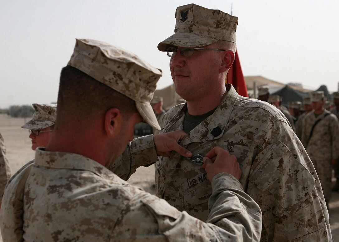Petty Officer 3rd Class Robert Less, a corpsman with Combat Logistics Battalion 6, 1st Marine Logistics Group (Forward), receives his Fleet Marine Force Warfare Specialist pin during a brief ceremony here June 2. Lee, a native of Jacksonville, N.C., received his Fleet Marine Force qualification along with two fellow Corpsmen within the battalion and spent several months preparing for the testing process. To receive the qualification, sailors must display general Marine Corps knowledge demonstrate their understanding in everything from unit organization, mission and equipment and must pass a series of written, oral and hands-on examinations.