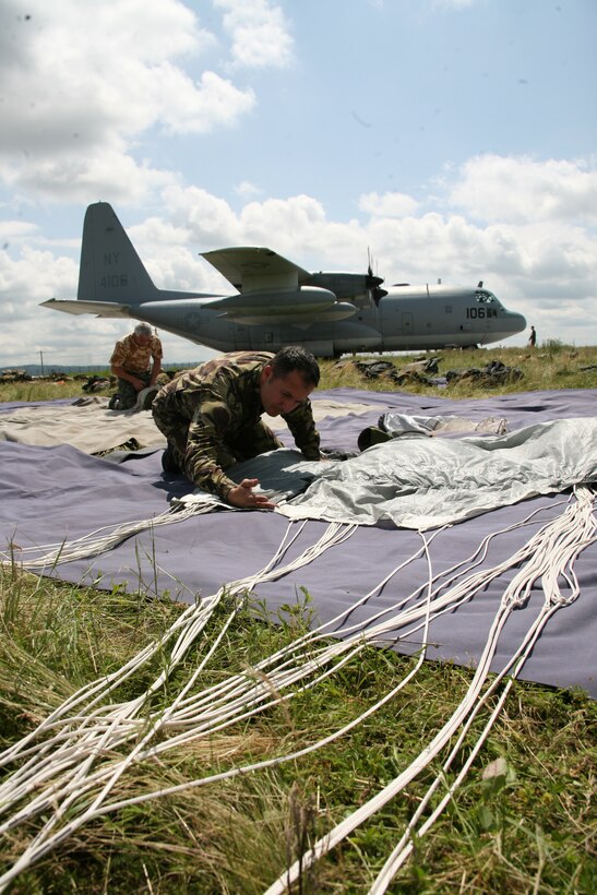 Romanian Staff Sgt. Ciobanu Ionel, a Romanian airborne soldier, repacks his parachute at Campia Turzii, Romania, June 3. About 75 Romanian paratroopers trained with U.S. Marines from Marine Aerial Refueler Transport Squadron 234 and VMGR-452, June 2-3. The Romanian and U.S. forces are scheduled to continue airborne training, June 8-9.
