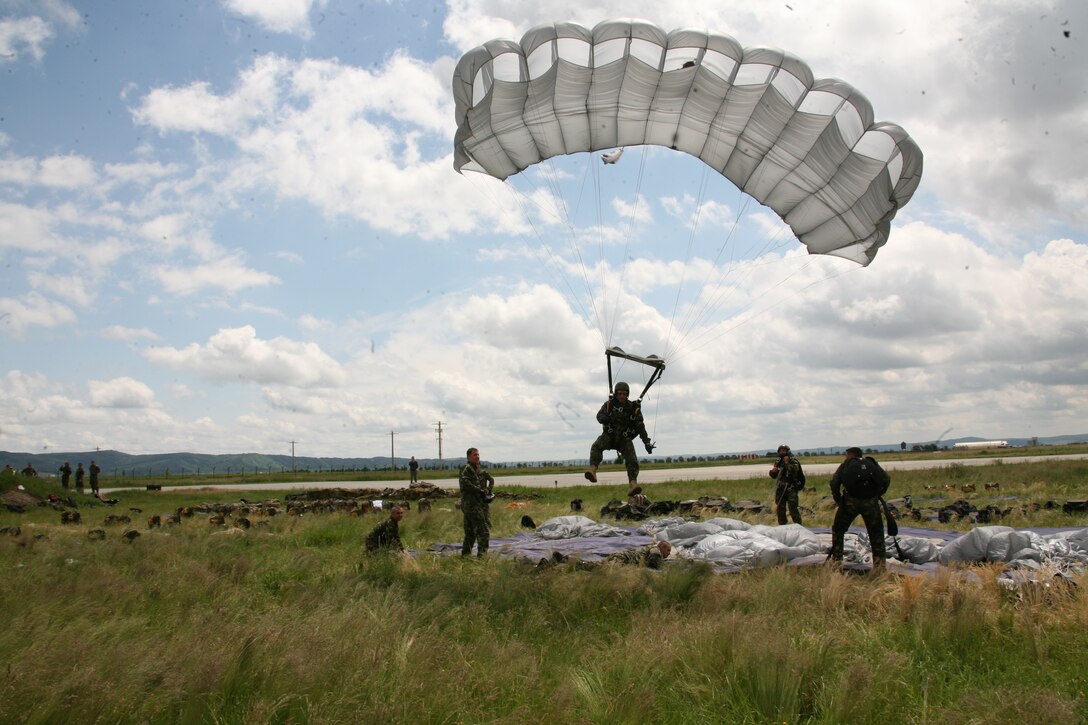 A Romanian paratrooper makes his landing on the grassy fields of Campia Turzii, June 3. Romanian paratroopers conducted static-line and military free fall airborne training with the help of U.S. Marine Corps KC-130 Hercules aircraft, June 2-3. Romanian and U.S. forces are slated to conduct more paratrooper training, June 8-9.
