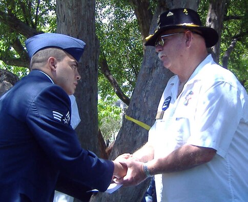 Senior Airman Isaiah Benavidez, from the 310th Mission Support Group, presents a commemorative pin to the father of one of Colorado's fallen veterans during the 11th Annual Veterans Memorial Day Tribute in Denver. Airmen from ARPC and the 310th MSG participated in the event May 29. (U.S. Air Force photo/Cindy Dewey)