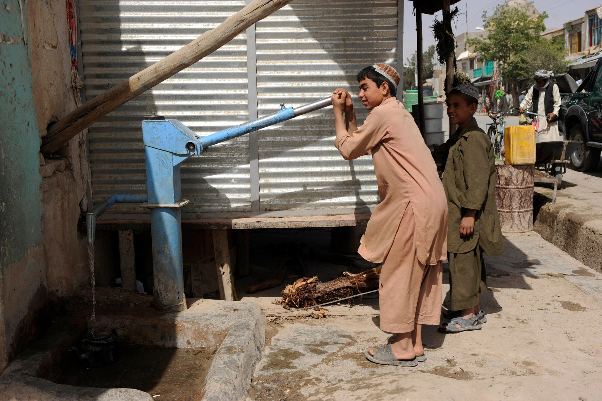 Afghan boys pump water on a bazaar street during a foot patrol by Provincial Reconstruction Team Zabul Airmen and Soldiers May 23, 2010, in Qalat City, Afghanistan. PRT Airmen help facilitate projects like Clean Water, a program that provides Afghan families with chlorine to kill bacteria in local water. (U.S. Air Force photo/Staff Sgt. Manuel J. Martinez)

