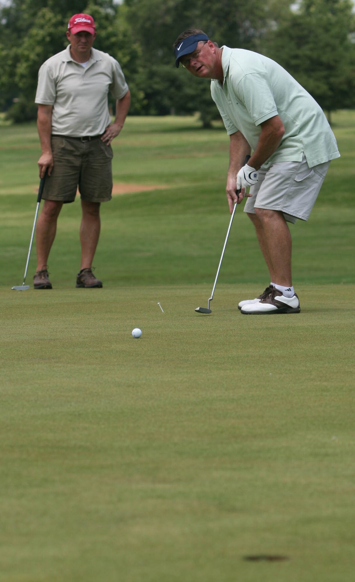 Mike Skinner takes a putt on hole nine May 27 during the 72nd Air Base Wing Golf Tournament while teammate Scott Walker watches. Merle Norman, Jim Rollings, Shawn Blatt and Joe Cruz won the best-ball tournament with a 23-under 49. (Air Force photo by John Stuart)
