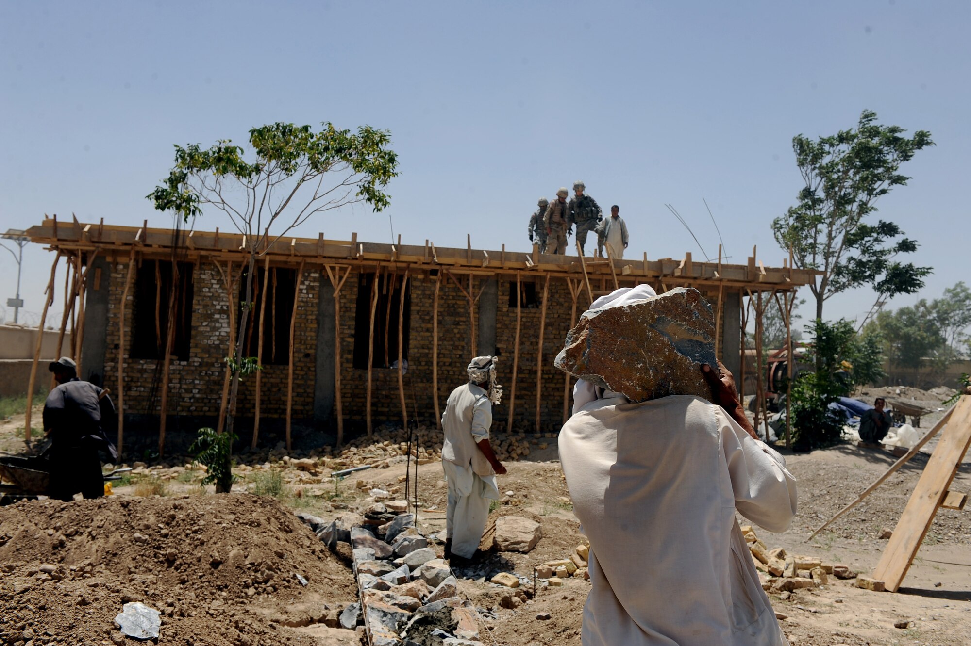 Afghan workers set the foundation for an indoor bathroom at the S.Malakhl Provincial Hospital, as First Lieutenant Keith Yelk, a civil engineer assigned to Provincial Reconstruction Team Zabul, checks the construction of a roof of an outpatient clinic during  a site visit May 27, 2010, in Qalat City, Afghanistan.  (U.S. Air Force photo/Staff Sgt. Manuel J. Martinez/released) 
