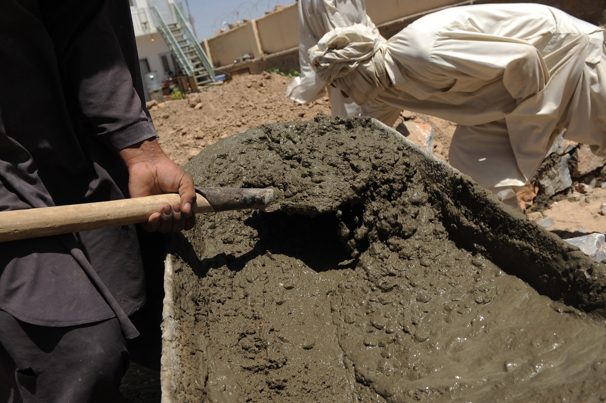 An Afghan man scoops cement as another arranges rocks for the foundation of a indoor bathroom for the S.Malakhl Provincial Hospital indoor bathroom facility, during a site visit by Provincial Reconstruction Team Zabul, May 27, 2010, in Qalat City, Afghanistan. (U.S. Air Force photo/Staff Sgt. Manuel J. Martinez/released) 