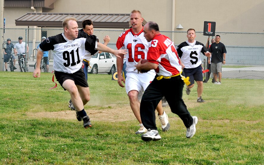 KUNSAN AIR BASE, Republic of Korea -- Chief Master Sgt. James Sanders, 8th Fighter Wing Command Chief, runs a play as Master Sgt. Warren Benge, 8th Force Support Squadron first sergeant, blocks Lt. Col. Kelly Harshbarger, 8th Civil Engineer Squadron commander, during the Chiefs vs. Eagles game May 21 at Kunsan Air Base, Republic of Korea. The Chiefs and Eagles game was a culmination of events that took place throughtout the Junior Enlisted Appreciation Day. The JEAD was hosted by members of the Kunsan Top III Association and supported by wing leadership.