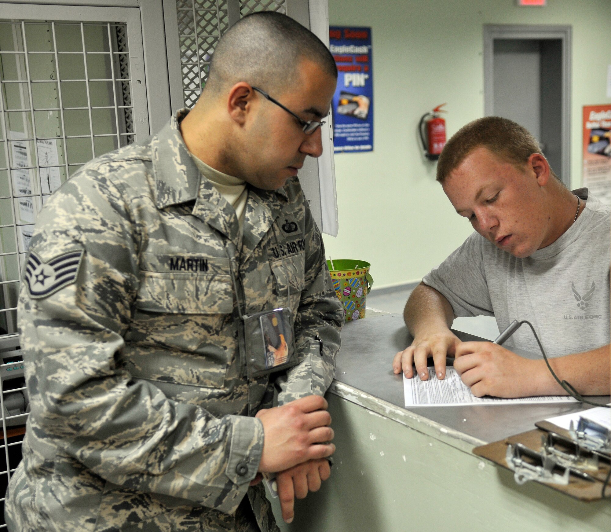 Staff Sgt. Eduardo Martin, 332nd Air Expeditionary Wing Financial Management Office customer service representative assists Airman 1st Class Travis Holt, 332nd Expeditionary Maintenance Squadron Ammunition Flight crewmember with an Eagle Cash application June 1, 2010 at Joint Base Balad, Iraq. Airman Holt is deployed from Shaw Air Force Base, S.C. and Sergeant Martin is deployed from Royal Air Force Base, Mildenhall. (U.S. Air Force photo/Staff Sgt. Phillip Butterfield)