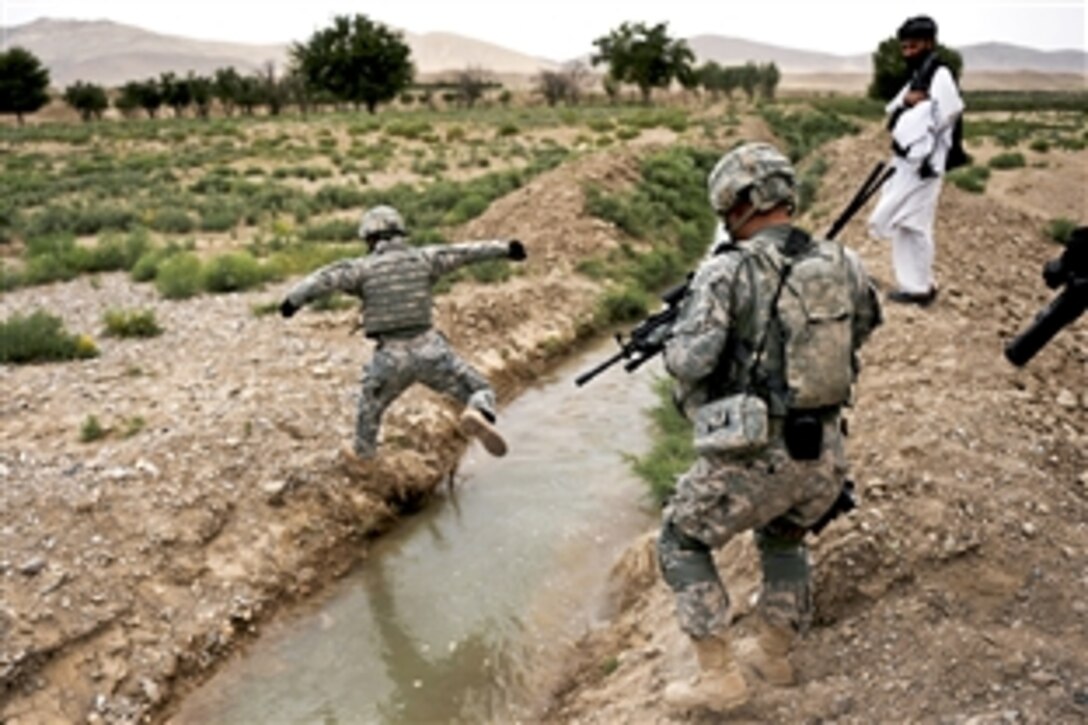An interpreter working with the Provincial Reconstruction Team Zabul crosses a creek on the way to Omarkhel village for a shura or meeting in Zabul province, Afghanistan, May 22, 2010. 
