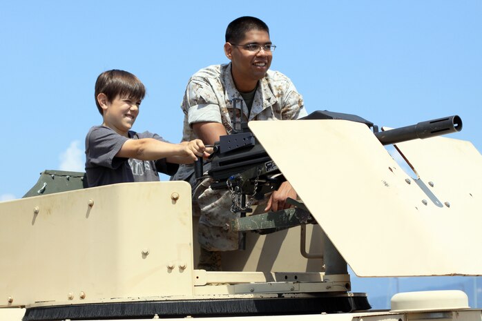 William Saunders, 12, seventh-grade Matthew C. Perry Advancement Via Individual Determination student pretends to fire a cleared MK19 attached to a humvee during the static display event near the IronWorks Gym here June 3. Saunders is assisted and supervised by Lance Cpl. Victor Contreras, a Marine Wing Support Squadron-171 armorer.