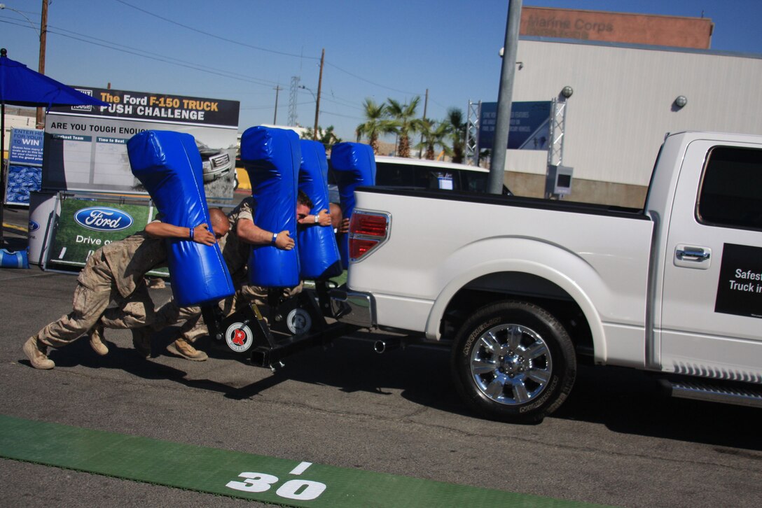 Private First Class Kyle Grove [left] and Lance Cpl. Frank Coleman, both infantrymen with Company E, 2nd Battalion, 9th Marine Regiment, use a football sleigh to push a Ford F150 truck up a hill during the Ford: Operation Drive One event at the Main Exchange's parking lot June 4. The other two members of their team, not pictured, were Lance Cpl. Joseph Durigon and Lance Cpl. Joey Depoyster, also infantrymen from Co. E, 2nd Bn., 9th Marines.