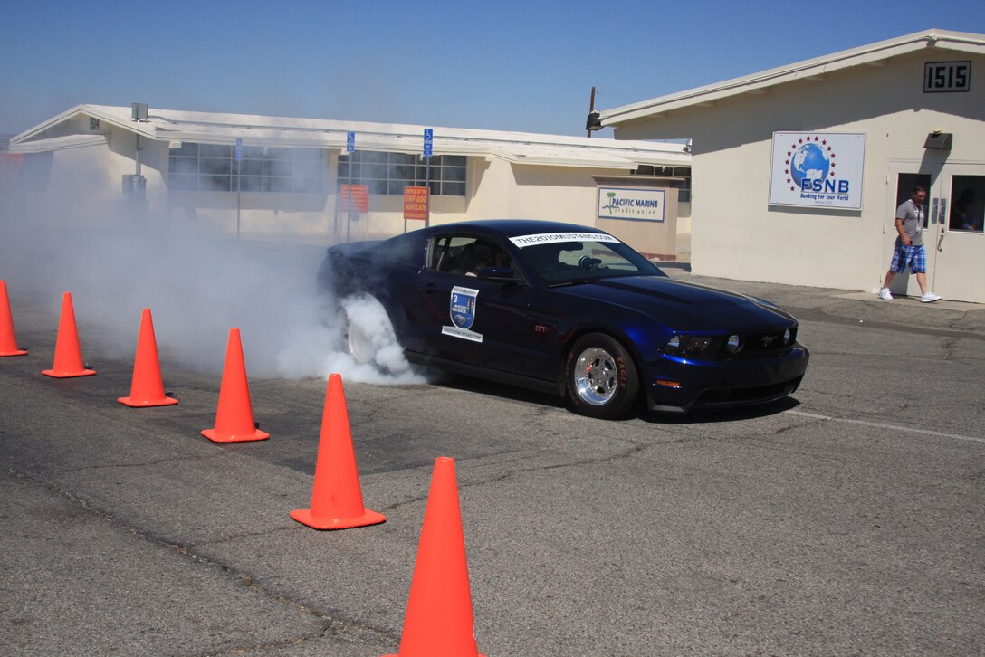 A professional driver demonstrates a "burn out" using a Ford Mustang decked out for drag racing during the Ford: Operation Drive One event June 4. Event goers also had a chance to test drive a Ford Mustang or Ford Fiesta on a precision driving course set up across the street from the Main Exchange and meet former wrestling champion Bill Goldberg.