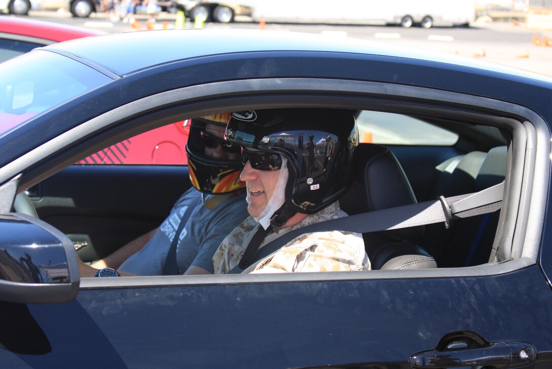 Staff Sgt. Kevin Brophy, the training staff noncommissioned officer in charge for Marine Wing Support Squadron 374, receives instructions from a professional driver as her prepares to test drive a new Ford Mustang on a precision driving course during the Ford: Operation Drive One event in the Main Exchange's parking lot June 4.