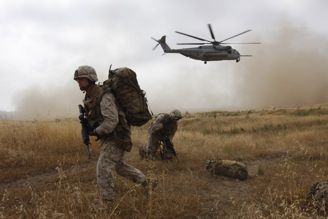 Sergeant Derrick C. Johnson, a squad leader with Company C, 1st Battalion, 7th Marine Regiment, heads across a field as a CH-53 Sea Stallion lifts off behind him. Battalion Landing Team 1/7 was the spearhead for exercise Dawn Blitz.
