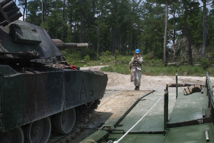 An M1 Abrams main battle tank from Alpha Company, 2nd Tank Battalion, 2nd Marine Division is guided off the raft by Cpl. Jonathan Dickens, a combat engineer and raft commander, during a training exercise with Bridge Company, 8th Engineer Support Battalion, 2nd Marine Logistics Group, across New River June 4, 2010, aboard Camp Lejeune. The exercise had the purpose to offer the Marines a real life experience and to take the tanks to SR-10 range, the only range sanctioned for the 120 mm cannon for semi-annual qualification.