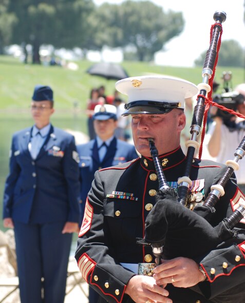 Gunnery Sgt. Joel Daniel, a bagpiper with the 1st Marine Division Band at Camp Pendleton, plays "Amazing Grace" during the Riverside National Cemetery Memorial Day ceremony. In the background is Staff Sgt. Aja Smith, 50th Aerial Port Squadron, who earlier in the ceremony recited the Airman's Creed. (U.S. Air Force photo by Megan Just)