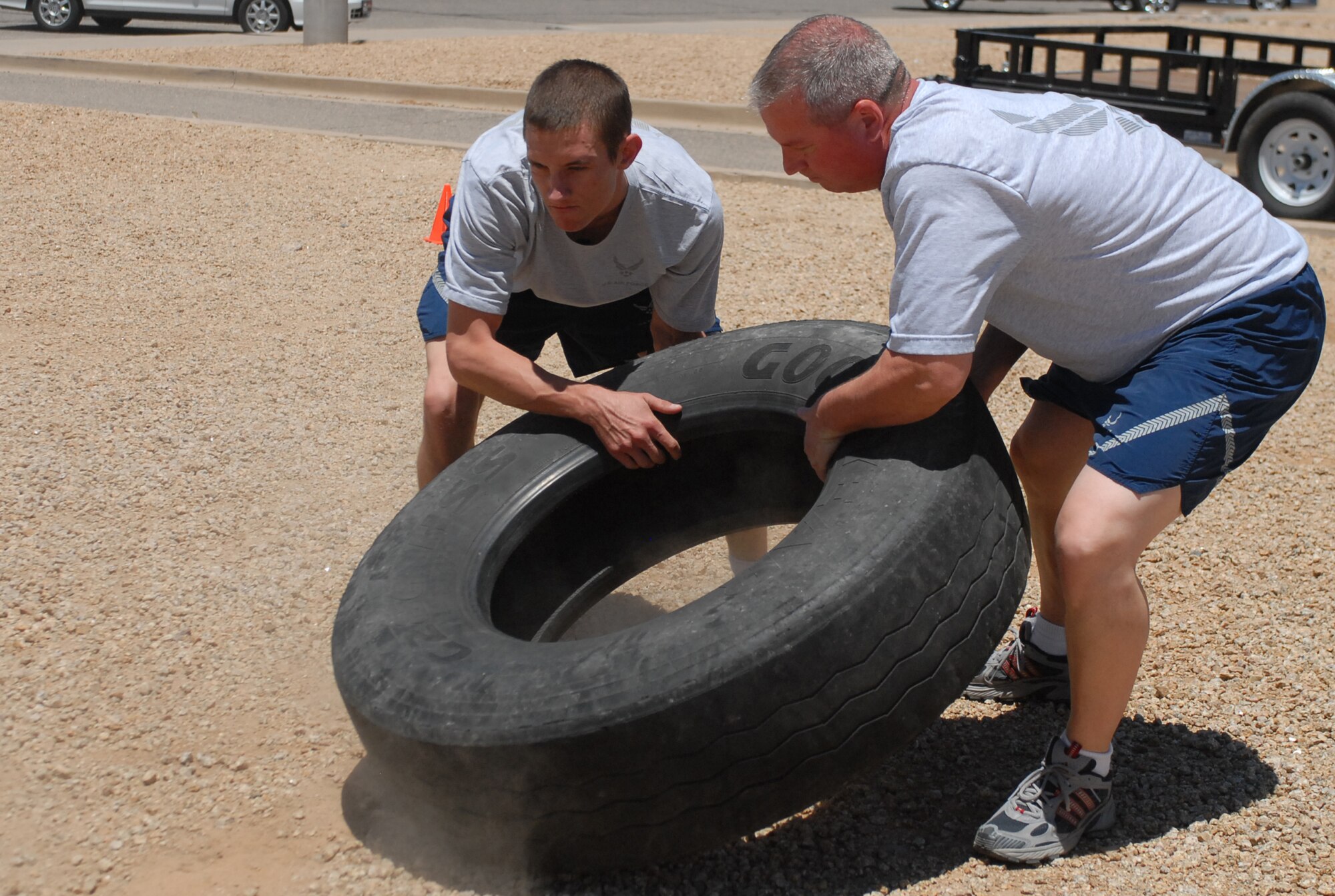 Senior Airman Philip Oliver and Technical Sergeant Richard Madge, 56th Security Forces Squadron, flip a tire during a Boots and Utes workout outside the Silver Wings Pool, May 27. (U.S. Air Force photo by Airman 1st Class Sandra Welch)   