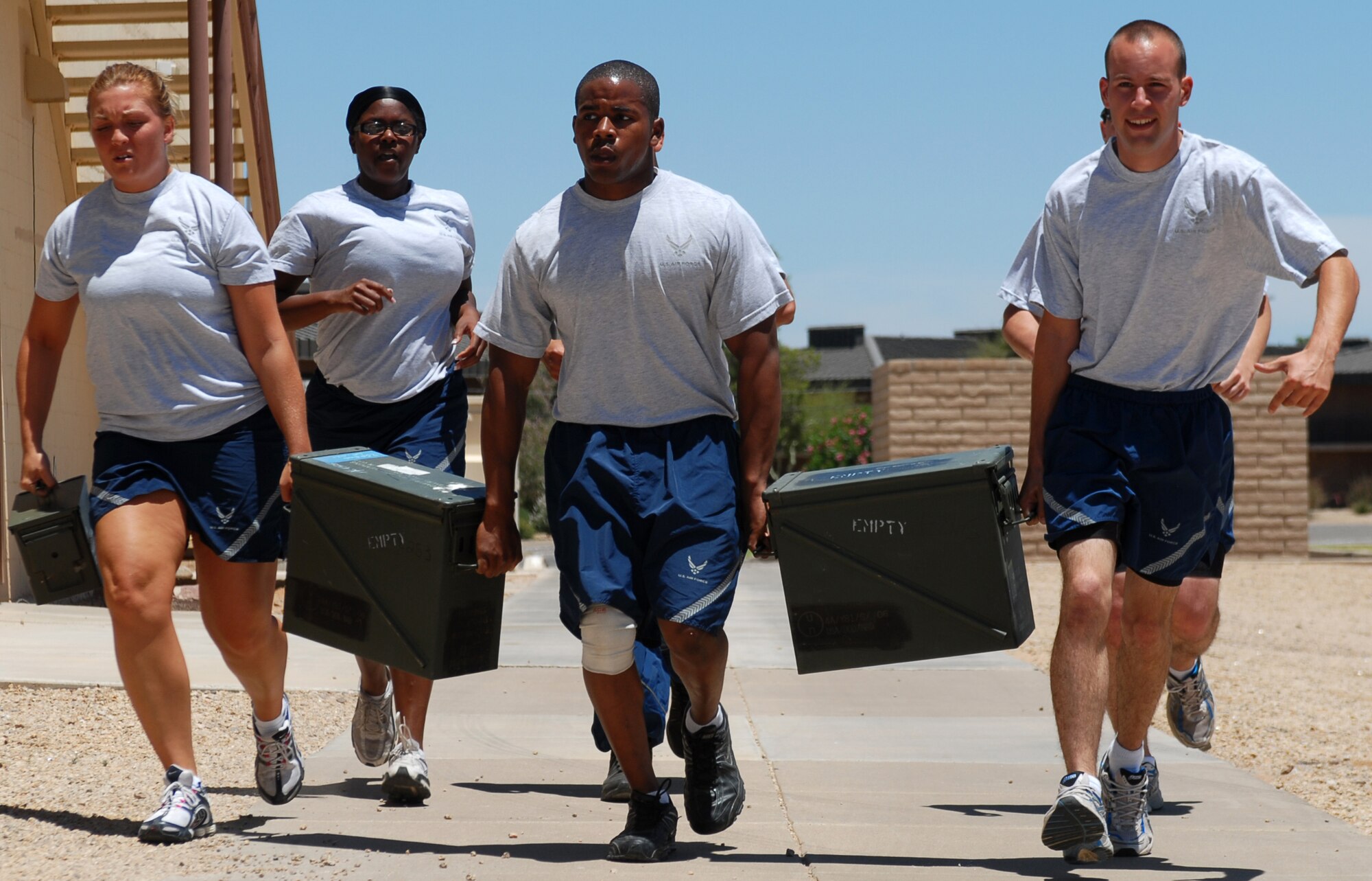 Security Forces members perform an ammo can carry from the soccer field to the Luke Cross Fit gym during a Boots and Utes workout, May 27. The large ammo cans weighing in at 70 pounds and smaller ammo cans weighing in at 25 pounds. (U.S. Air Force photo by Airman 1st Class Sandra Welch)