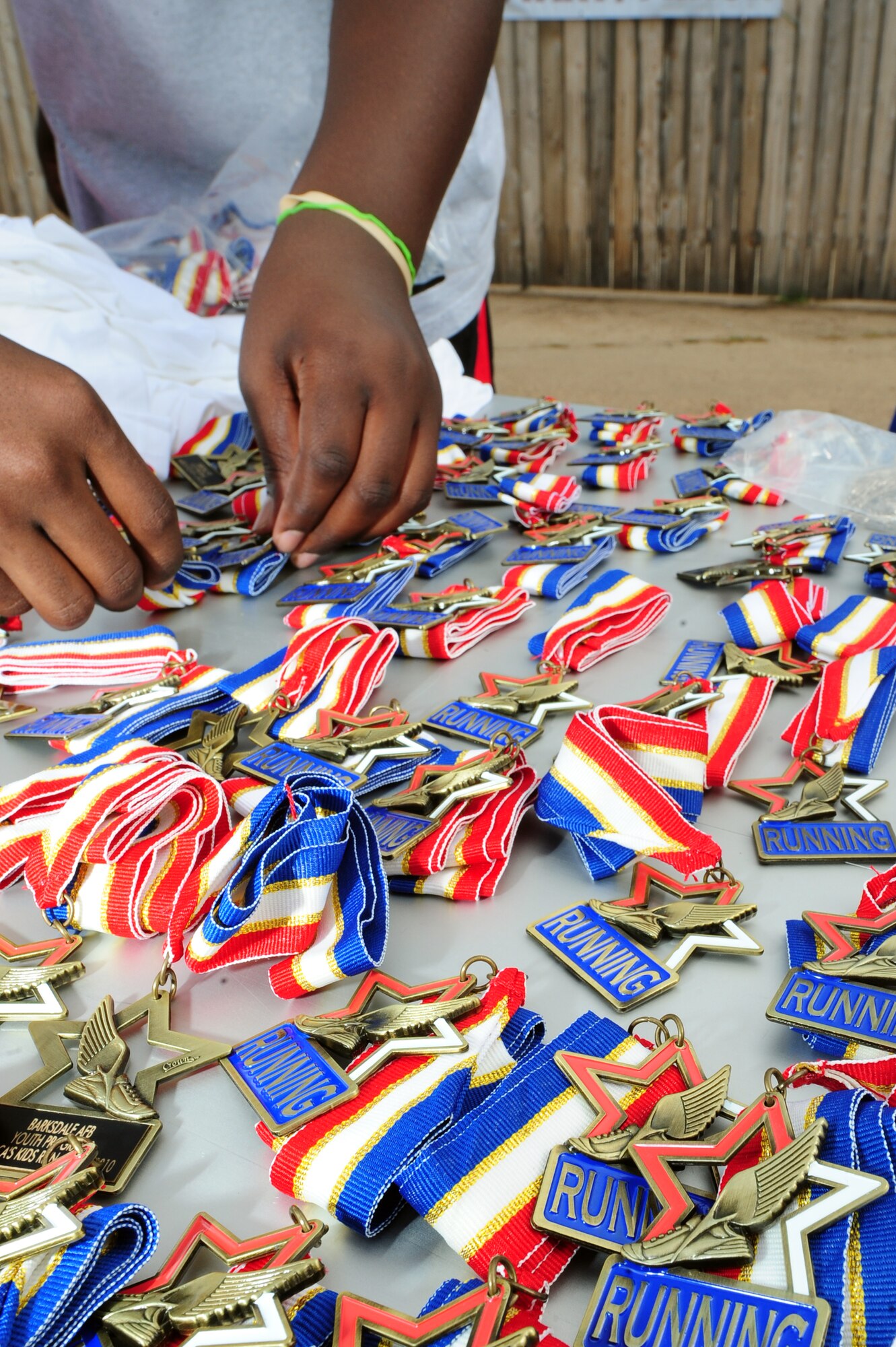 BARKSDALE AIR FORCE BASE, La. – A youth center volunteer lays ‘running medals’ out for America’s Armed Forces Kids Run participants outside the fitness center June 4. Participants, ranging from ages 5-13, ran a half-mile, one mile or two miles depending on their age category. (U.S. Air Force photo by Senior Airman Joanna M. Kresge)