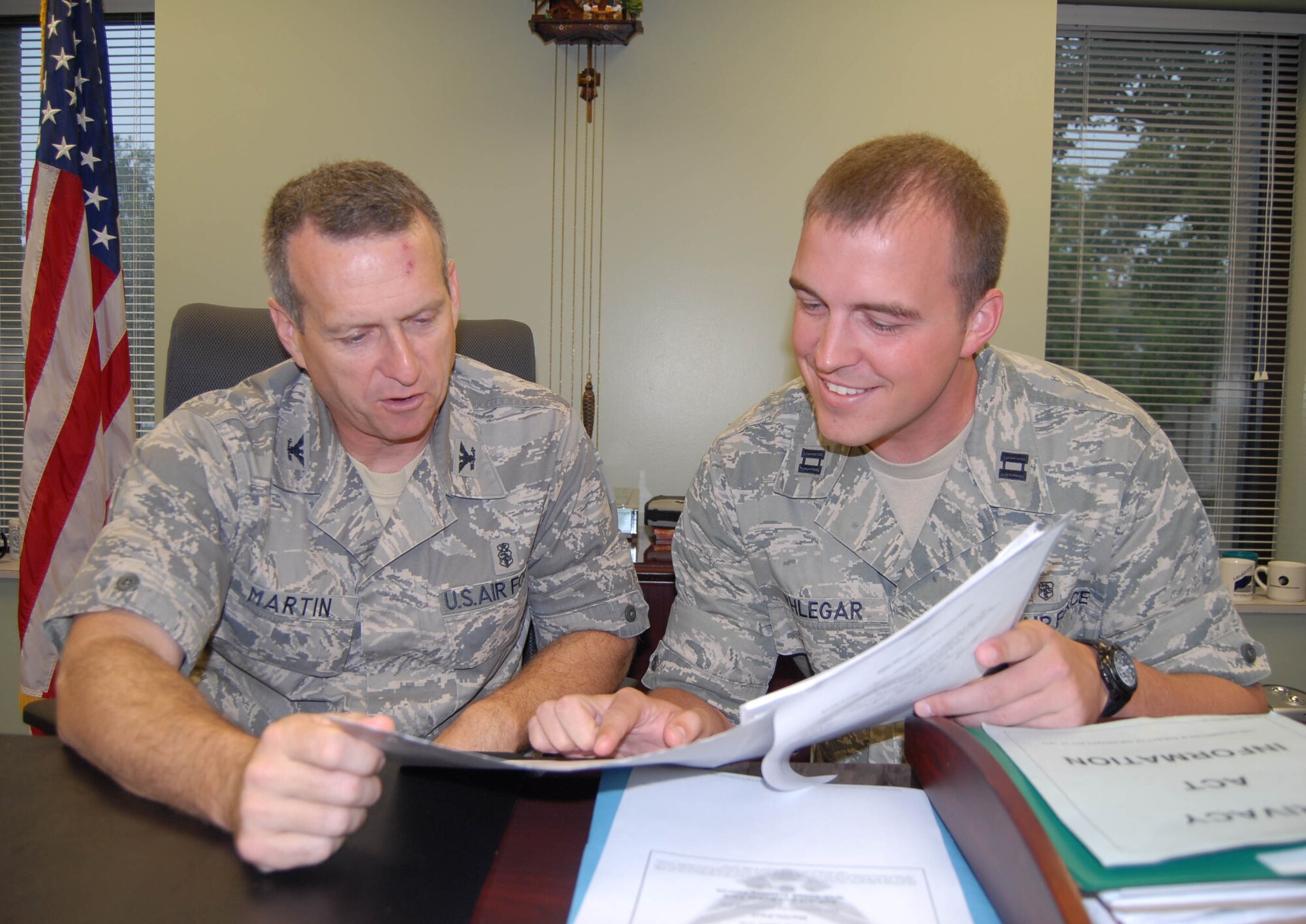 Col. Paul Martin, 43rd Medical Group, Commander, (left) reviews a decorations package with Capt. Archie Phlegar, 43rd MDG, in his office, June 1. Captain Phlegar received the Commander’s Coin for his exceptional performance June 1. (U.S. Air Force Photo/ 1st Lt. Cammie Quinn) 