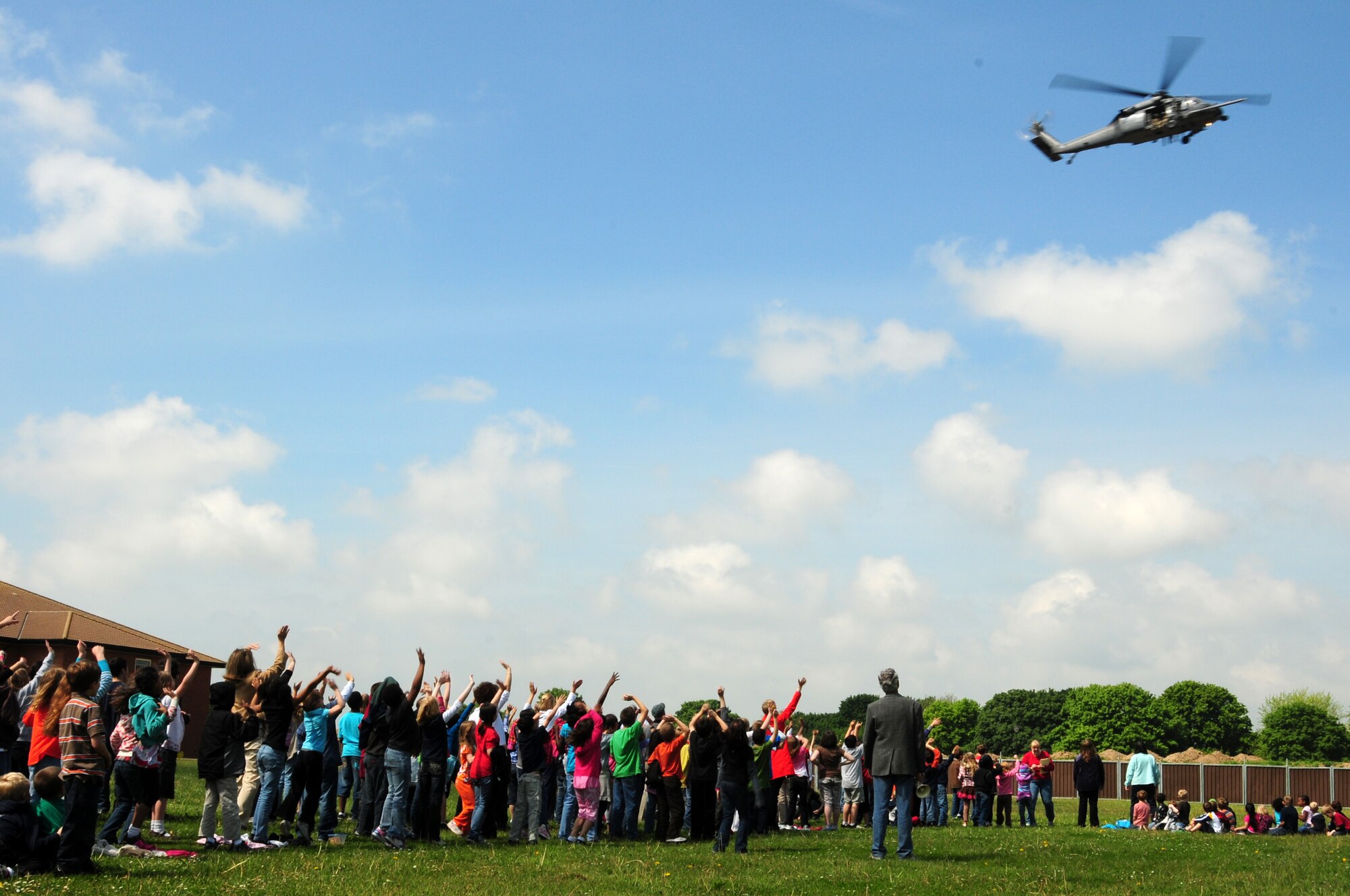 RAF Feltwell Elementary School students wave as an HH-60G Pavehawk helicopter from the 56th Rescue Squadron flies by June 2. The helicopter flew by before landing at the school so the aircrew could teach the children about their mission in the U.S. Air Force and the capabilities of their helicopter.   (U.S. Air Force photo/Airman 1st Class Lausanne Morgan)