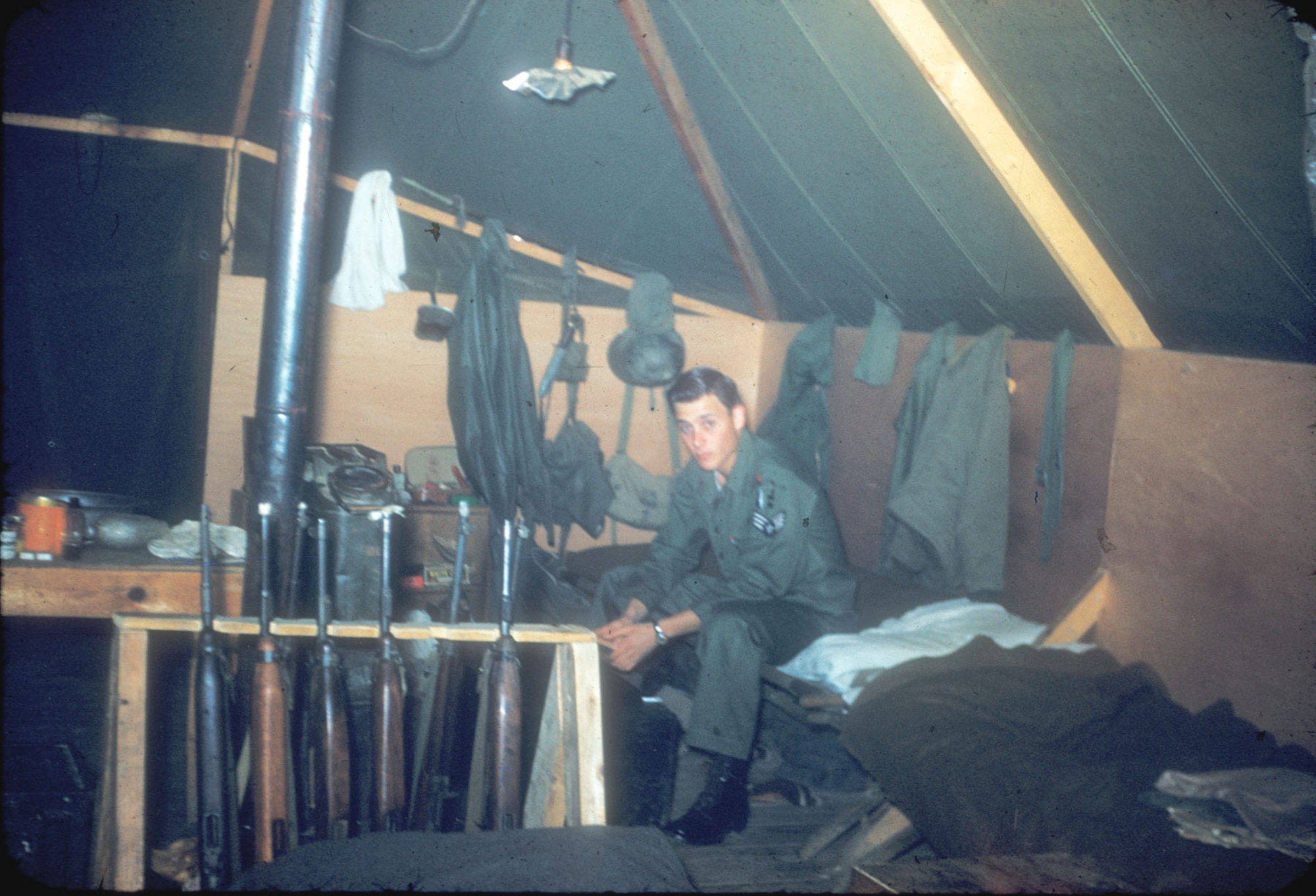 Airman 1st Class Richard Heimerich in his corner of a barracks tent at K-47 (Chunchon). Note the gun rack with several carbines readily available for use in an emergency. (U.S. Air Force photo)