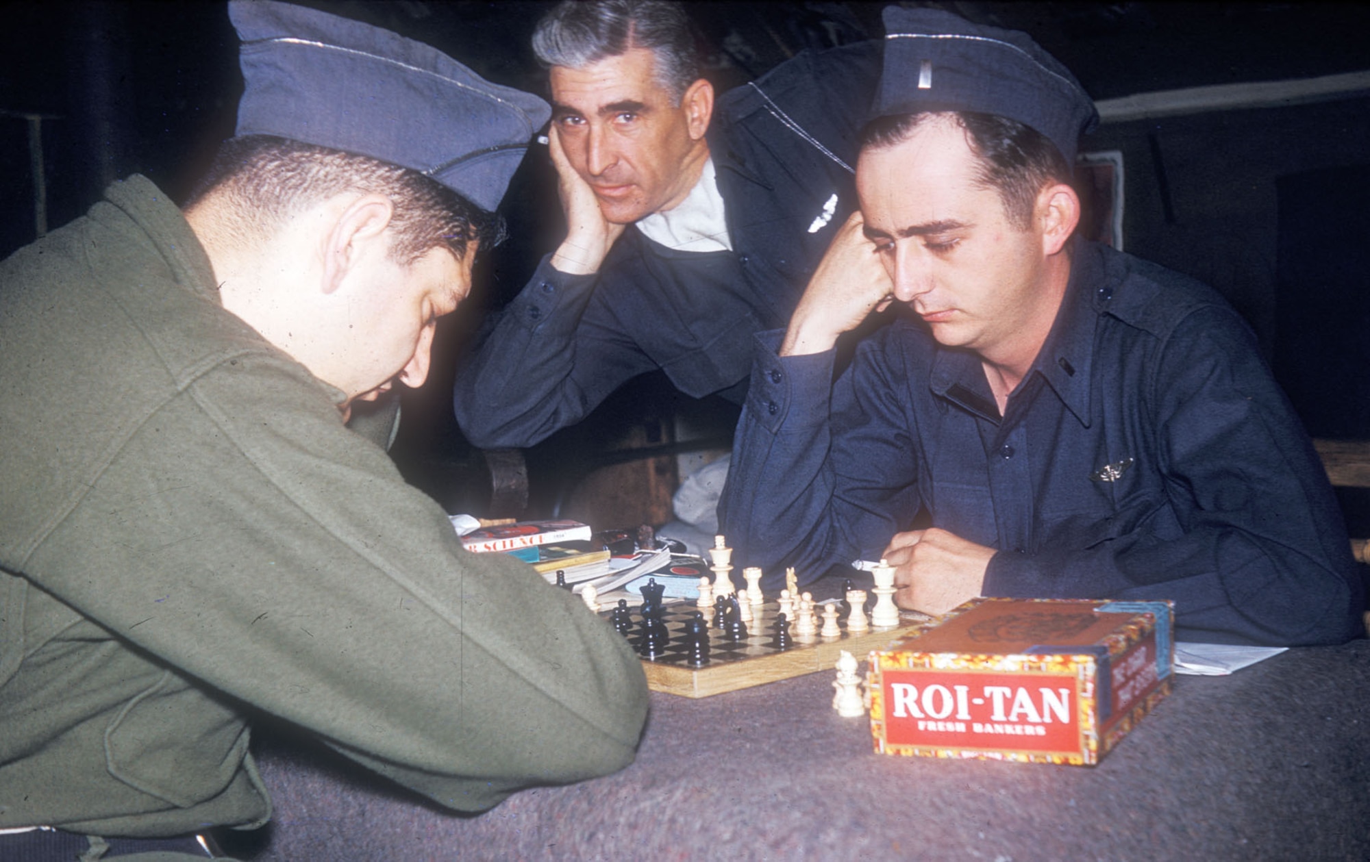 Capt. Evens and 1st Lt. Baldwin pass the time immersed in a chess game while Capt. Diff watches. (U.S. Air Force photo)