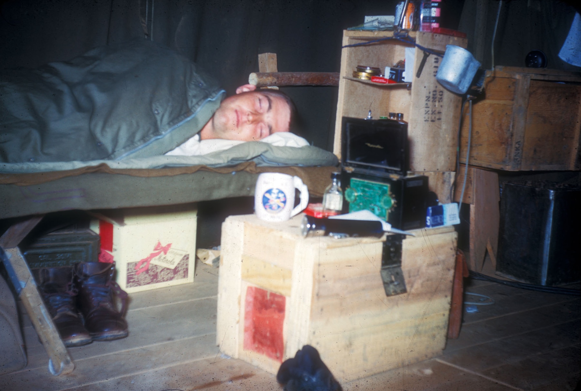 This Airman is stealing some badly-needed rest between missions. His meager possessions are kept in and on scavenged supply crates. (U.S. Air Force photo)