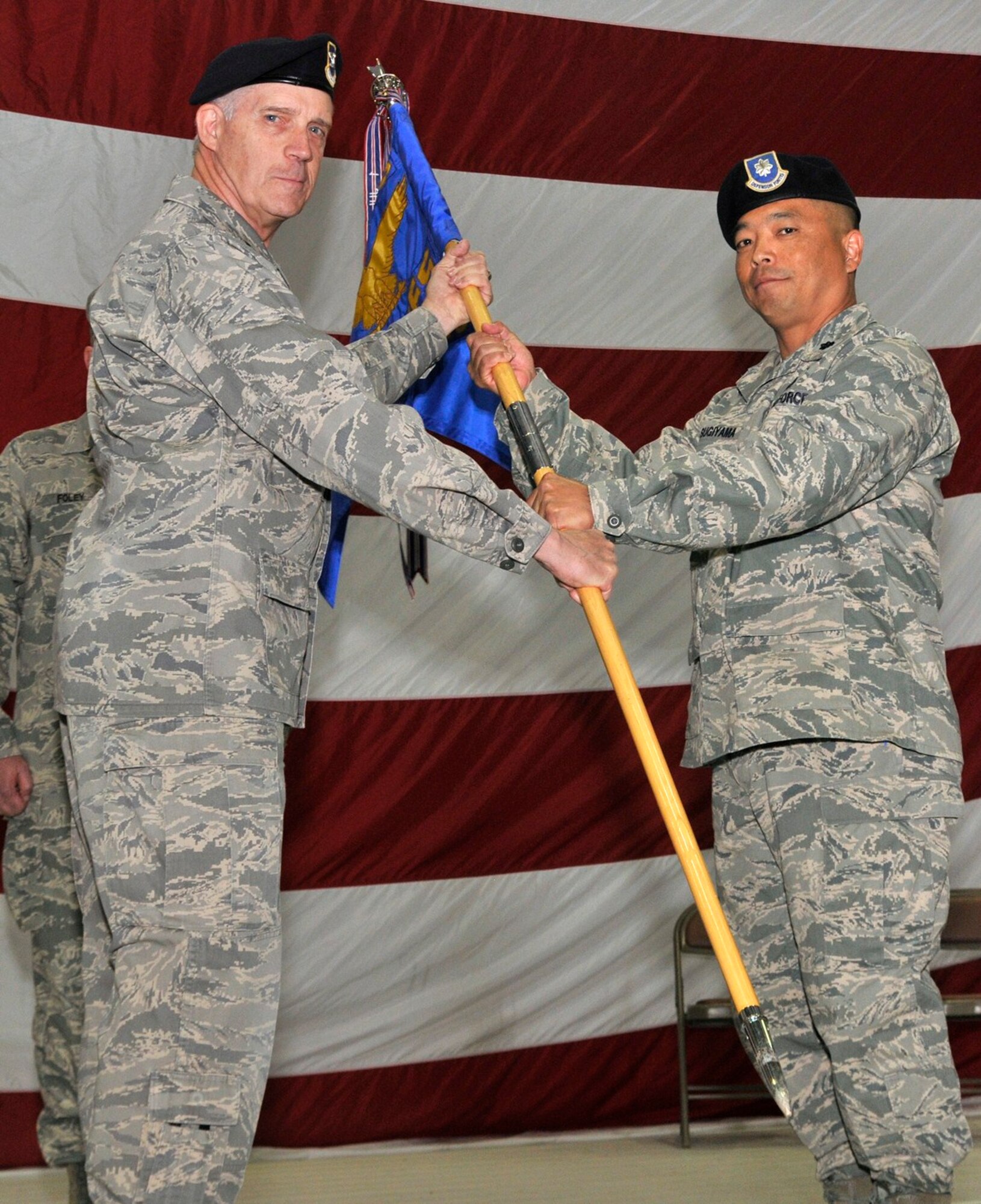 Col. John Probst, 341st Security Forces Group commander, passes the 341st Missile Security Forces Squadron guidon to Lt. Col. Steve Sugiyama, the new 341st MSFS commander at the change of command ceremony May 27. (U.S. Air Force Photo/John Turner)