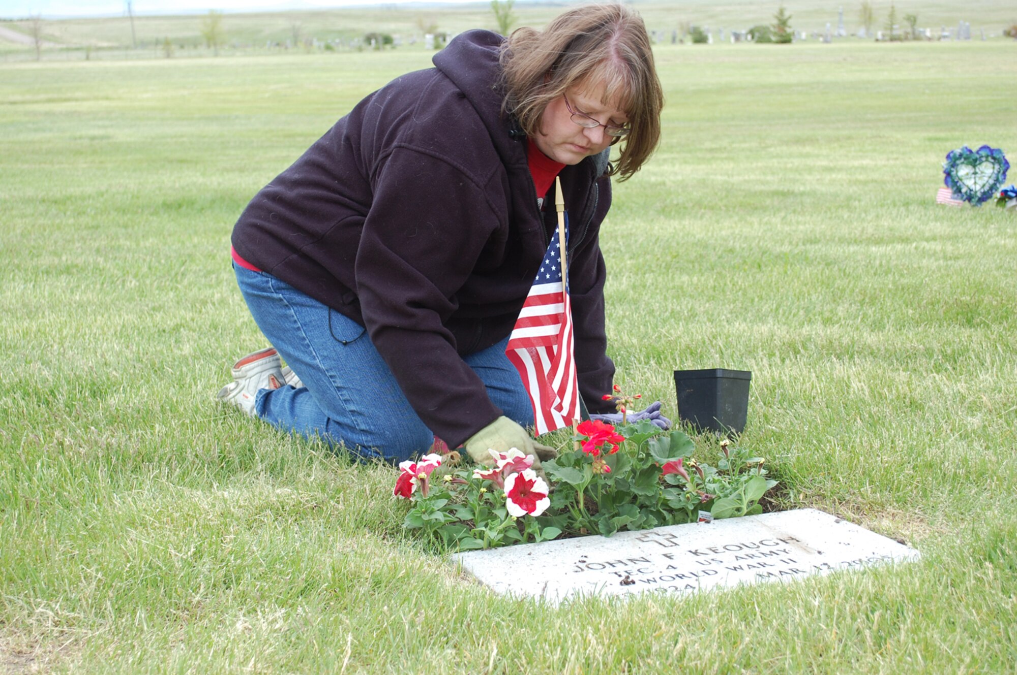Lori Nelson plants flowers around the grave of her uncle, John Keough, who served in the Army during World War II. (U.S. Air Force Photo/Airman 1st Class Kristina Overton)