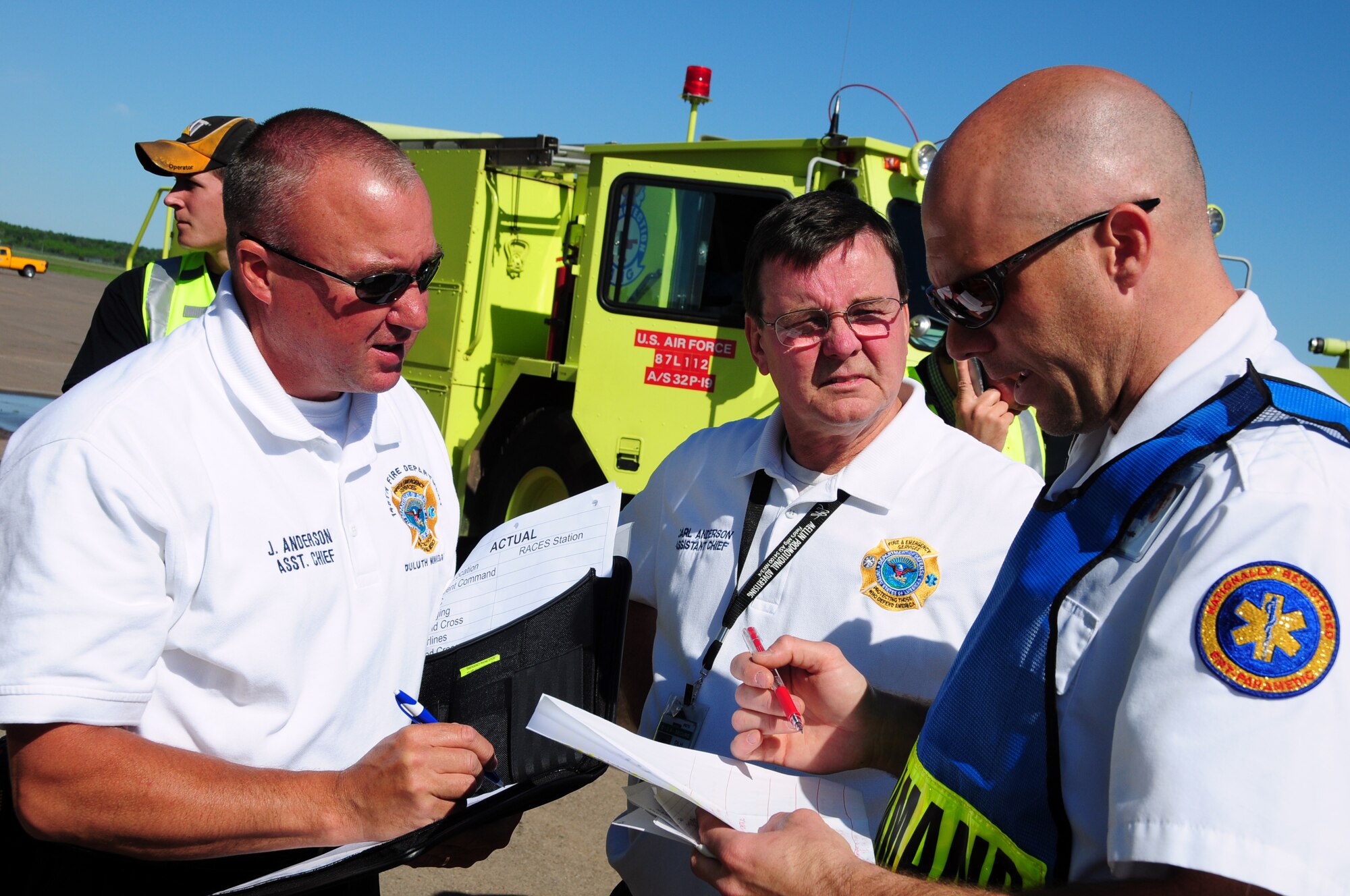 U.S. Air National Guard Fire Fighter Joel Anderson (left) and Carl Anderson, both 148th Fighter Wing Assistant Fire Chiefs, communicate with aGold Cross EMT during a Major Accident Response Exercise (MARE) of a commercial airliner crash at the  Duluth International Airport, Minn., June 3, 2010. The MARE was held in conjunction with local, state and federal emergency response agencies to test and validate emergency response capabilities. (U.S. Air Force photo by Master Sgt. Jason W. Rolfe/Released)