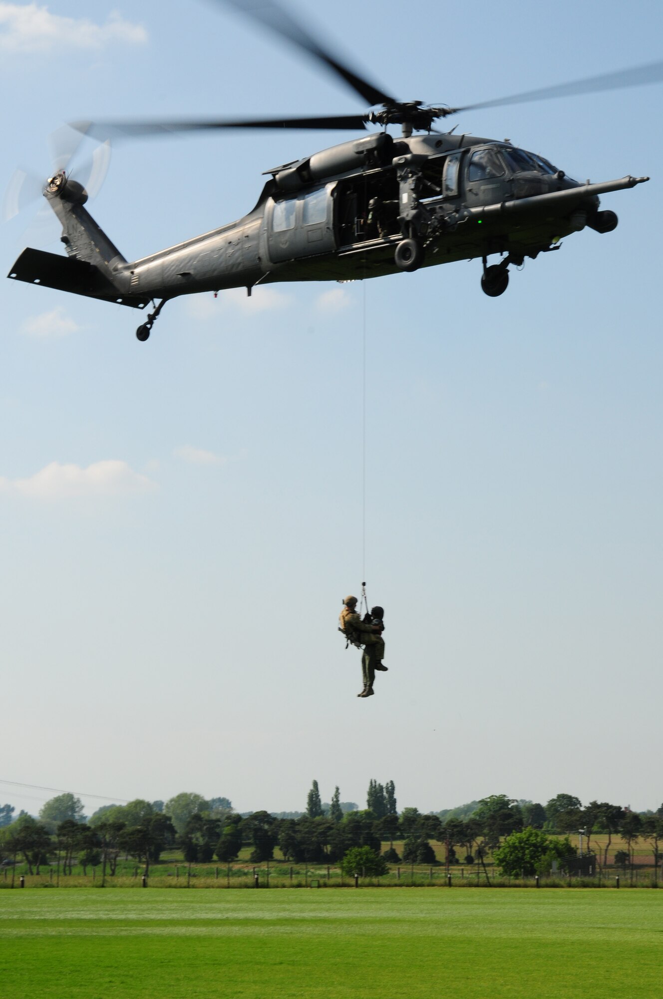 Senior Airman Bradford Thornburg, 56th Rescue Squadron pararescueman, hoists Col. Jay Silveria, 48th Fighter Wing commander, from a helicopter at RAF Lakenheath June 2.  This was Colonel Silveria’s final flight aboard one of the 56th RQS’s HH-60G Pavehawk helicopters.  The colonel was dropped off at the soccer fields behind Lakenheath High School just in time to speak to the graduating seniors as their special guest. (U.S. Air Force photo/Airman 1st Class Lausanne Morgan)