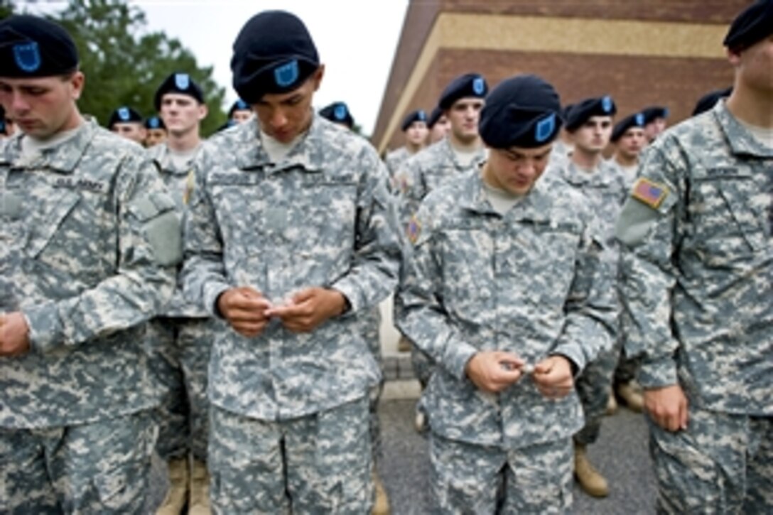 Recruits enrolled in the  Basic Combat Training Course on Fort Benning, Ga., admire coins Navy  Adm. Mike Mullen, chairman of the Joint Chiefs of Staff, gave them after an all-hands call, June 4, 2010.