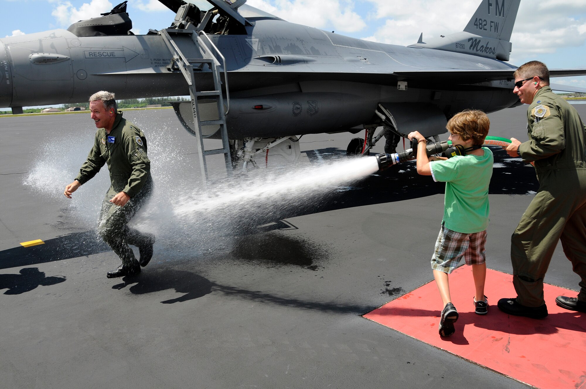 Brig. Gen. Binger's son with help from Lt. Col. Michael Lesman, gives his father a good soaking courtesy of a fire hose after completing his final flight in an F-16 on June 3.  Next week General Binger will head to his new job at Robins Air Force Base, Ga., to become commander of the newly formed Force Generation Center, Headquarters Air Force Reserve Command. (U.S. Air Force photo/Tim Norton)