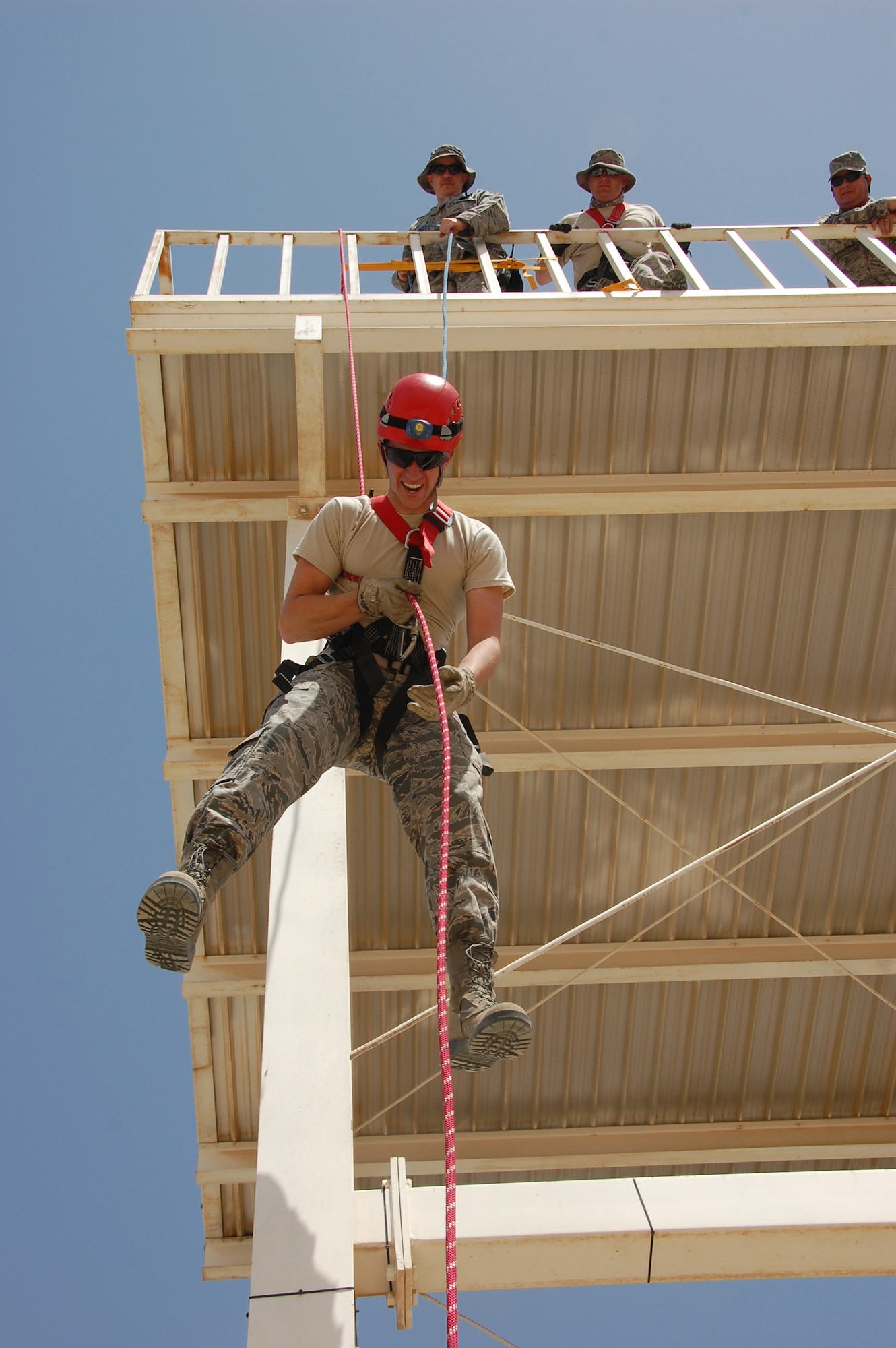 Members of the 386th Expeditionary Civil Engineer Squadron Fire Department spot U.S. Air Force cadet Jeff Larkin, a Texas native, as he descends from a tower as part of a high angle rescue training session here June 5, 2010 at an air base in Southwest Asia. Twenty cadets are visiting the 386th Air Expeditionary Wing this month to experience military life downrange. (U.S. Air Force photo by Staff Sgt. Lakisha A. Croley/Released)
