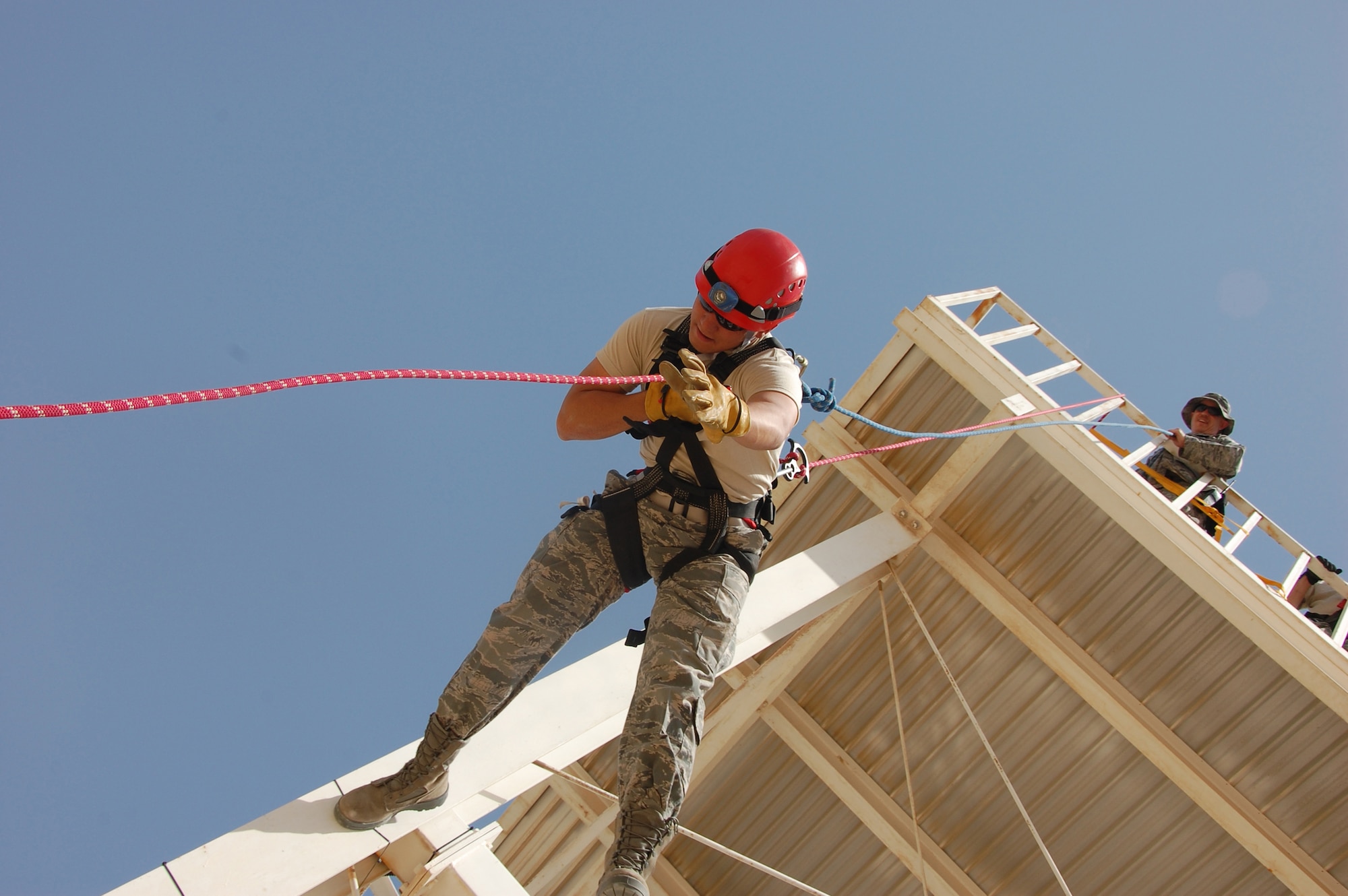 U.S. Air Force Master Sgt. Peter Soergel, 386th Expeditionary Civil Engineer Squadron A/C Training/ Fire and Emergency Services, assists U.S. Air Force Cadet Josh Stevens during a high angle rescue training session here June 5, 2010 at an air base in Southwest Asia. Twenty cadets are visiting the 386th Air Expeditionary Wing this month to experience military life downrange. (U.S. Air Force photo by Staff Sgt. Lakisha A. Croley/Released)